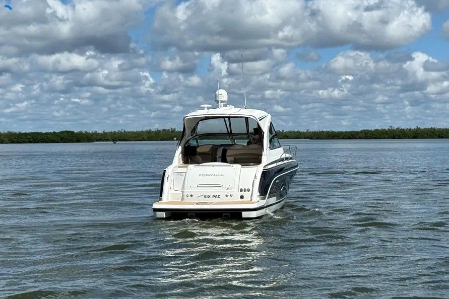 A white motor yacht cruises on calm water under a cloudy sky.