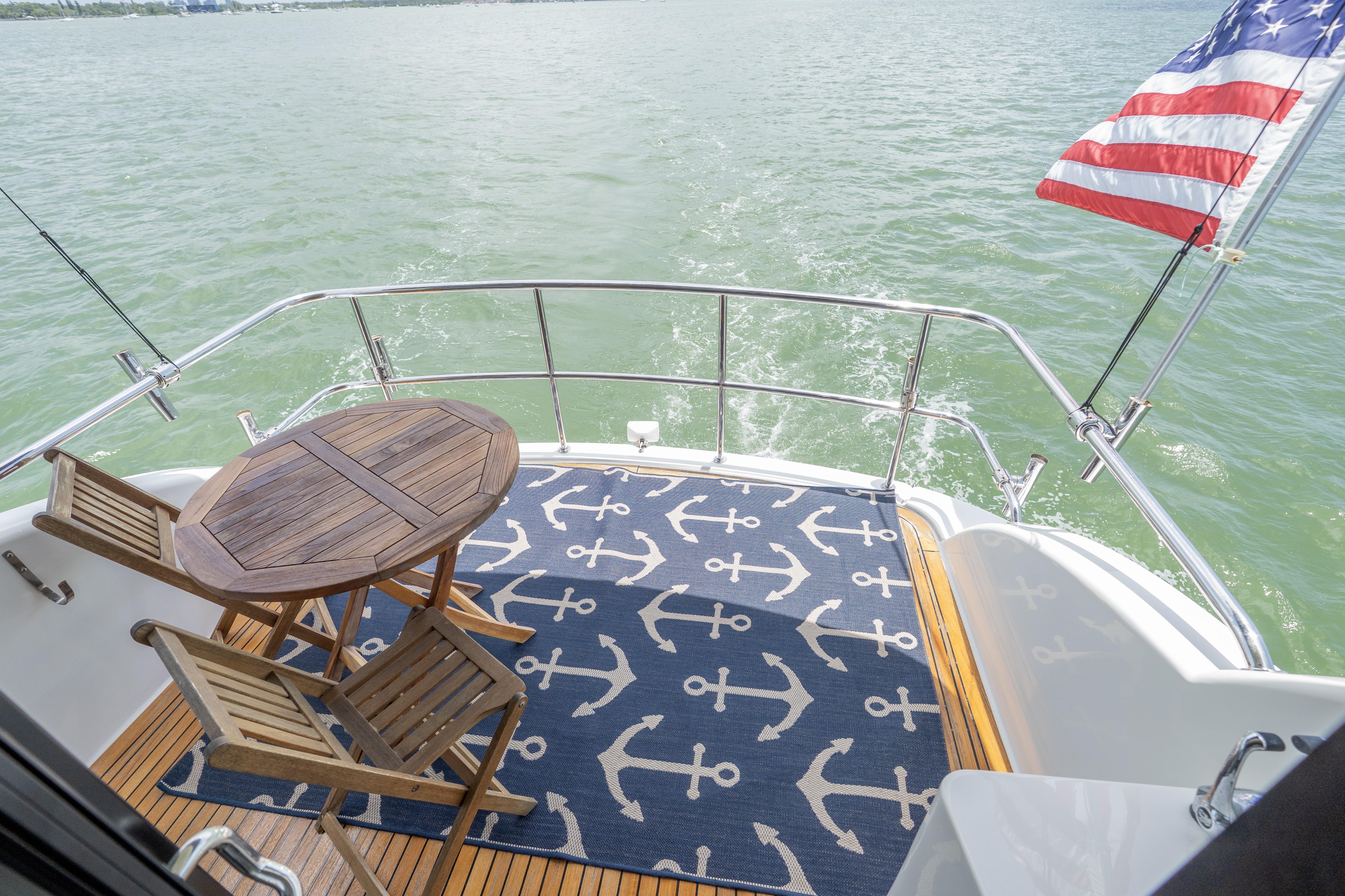 2008 Maritimo 52 yacht deck with anchor-themed rug and wooden furniture.