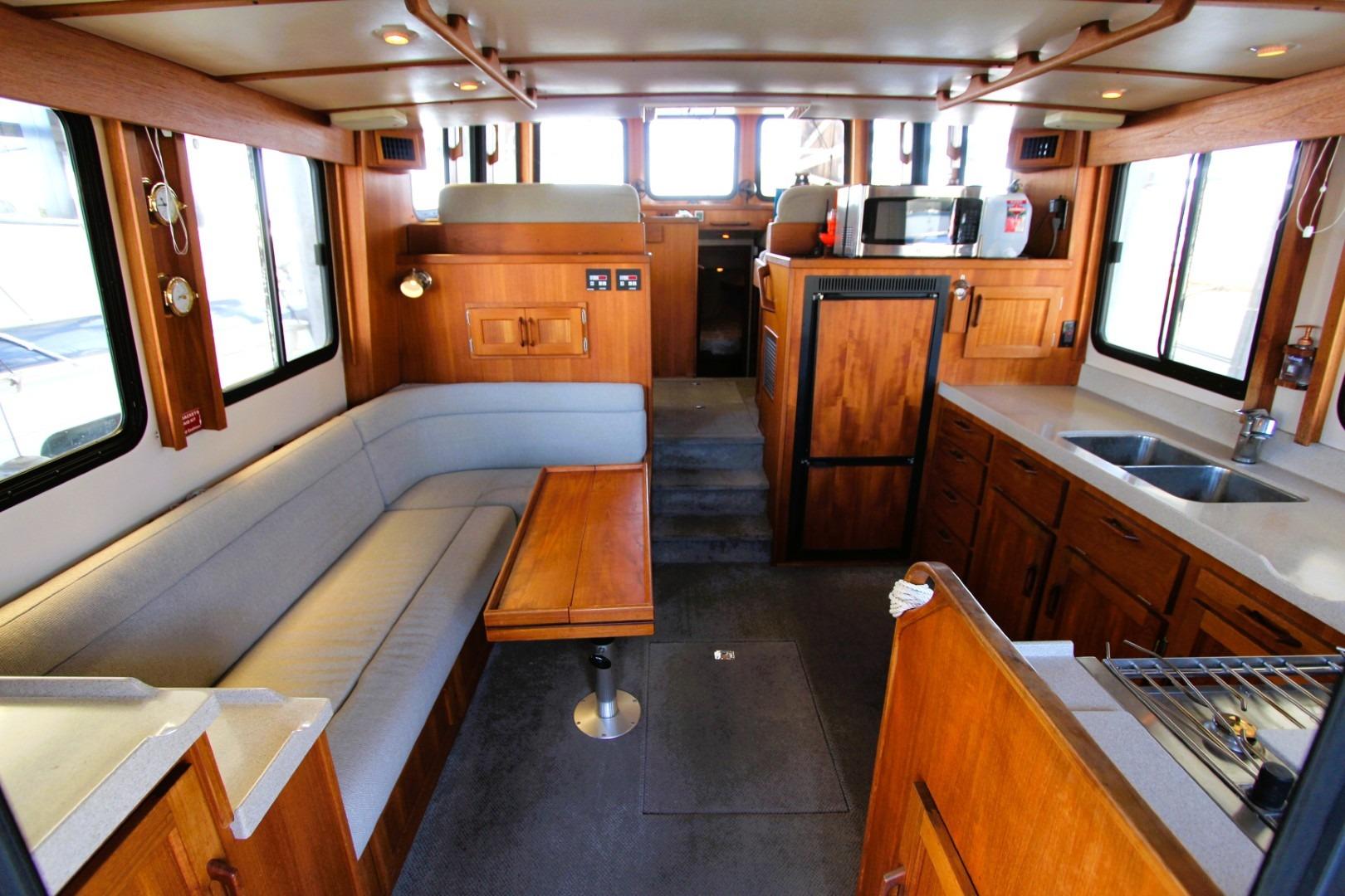 Interior of a 2002 Nordic Tug 37, featuring a cozy seating area and kitchen amenities.