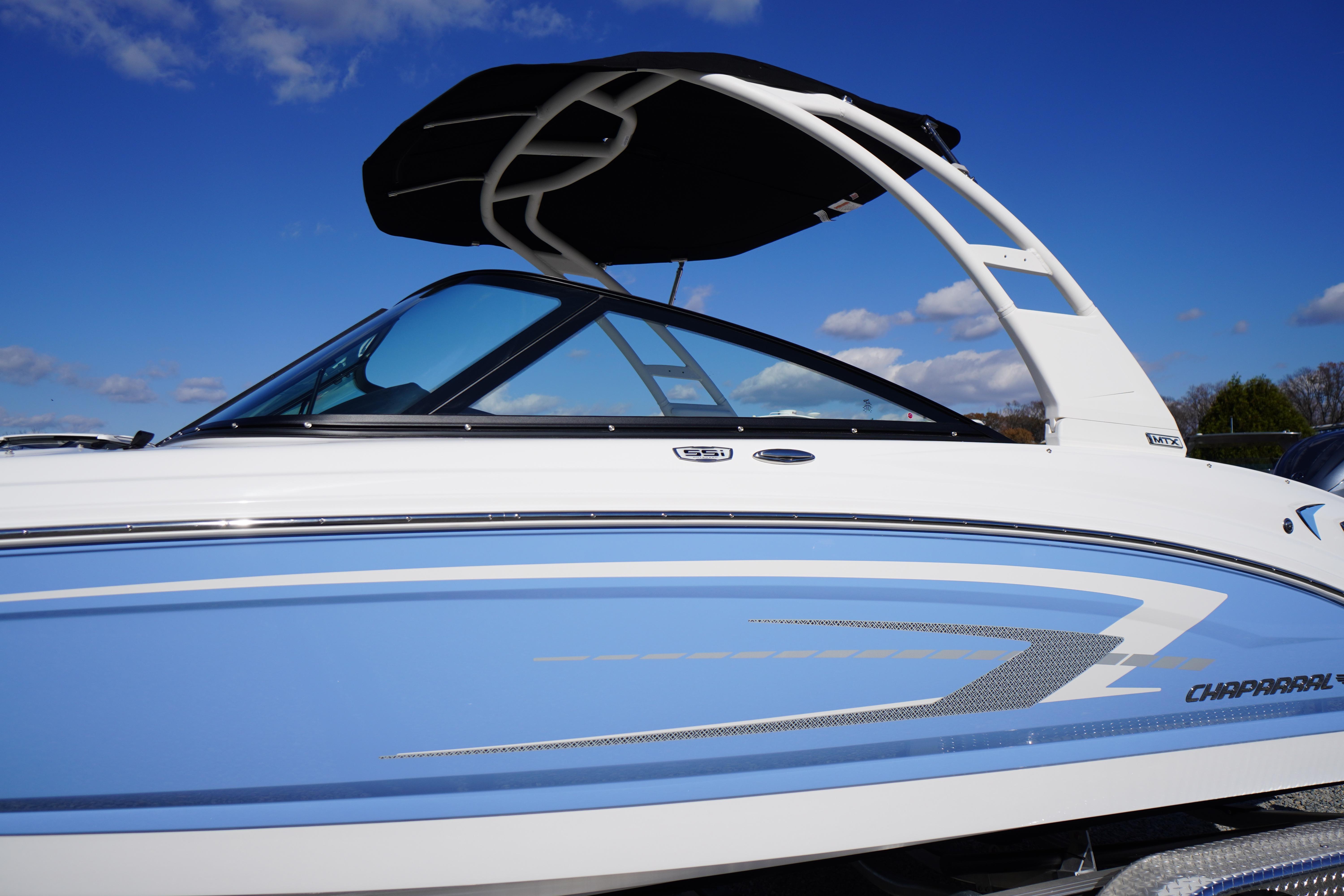 2026 Chaparral 23 SSi OB boat with blue and white design under clear sky.