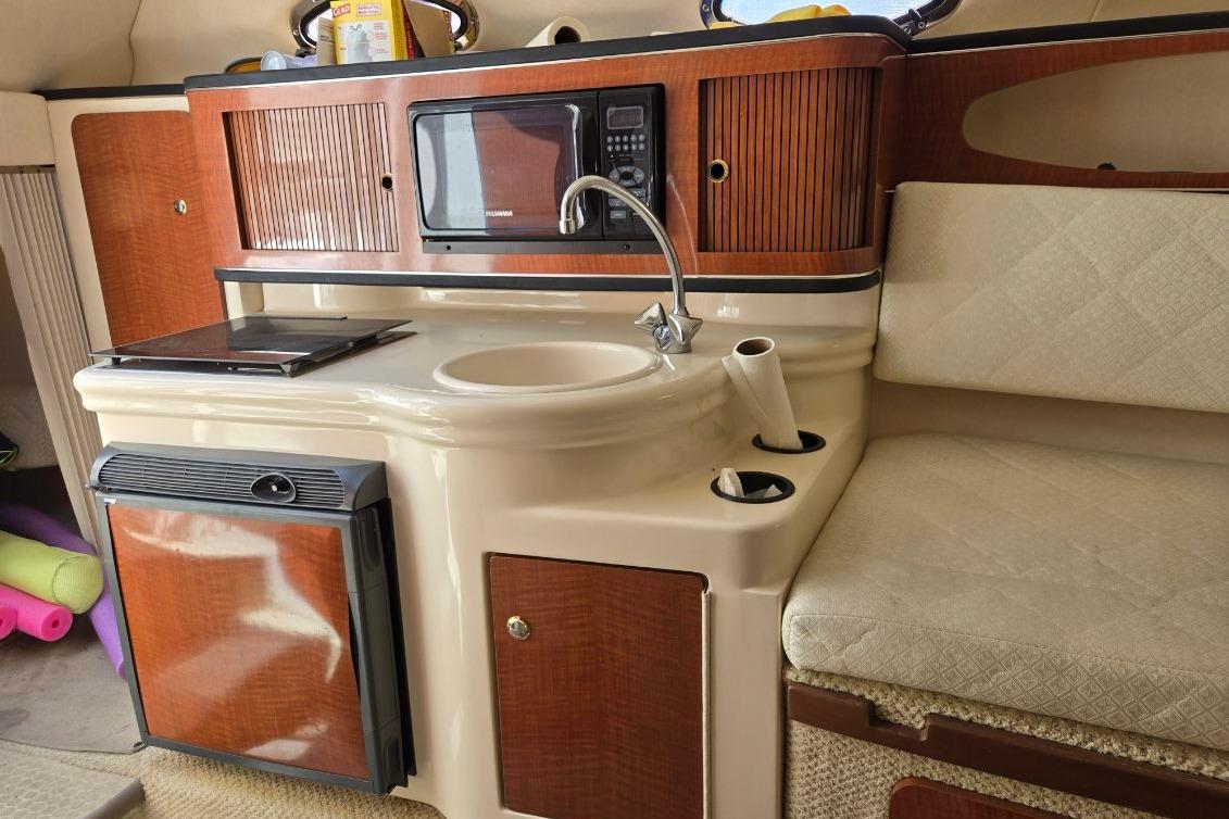 2004 Sea Ray Sundancer 260 interior with kitchenette, featuring sink, microwave, and seating.