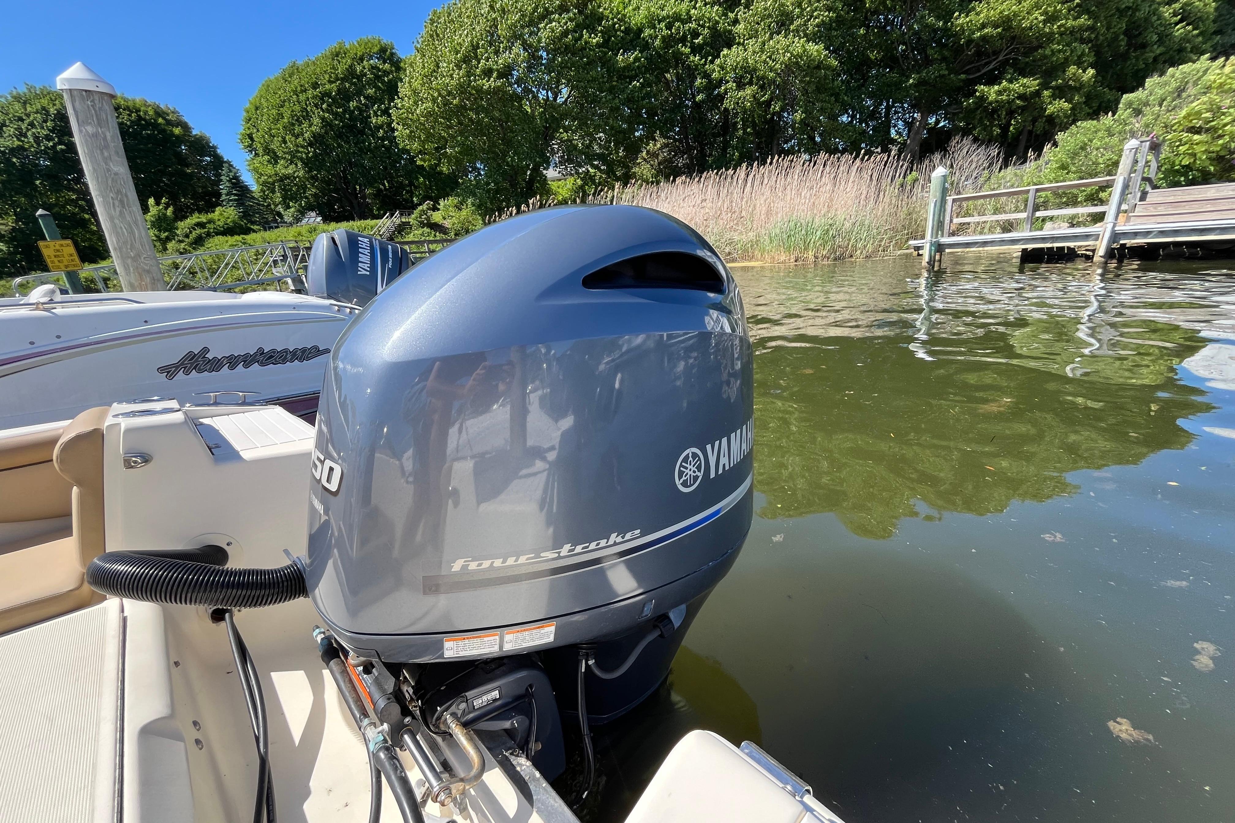 2017 Scout 210 Dorado boat with Yamaha outboard motor docked by lush greenery.