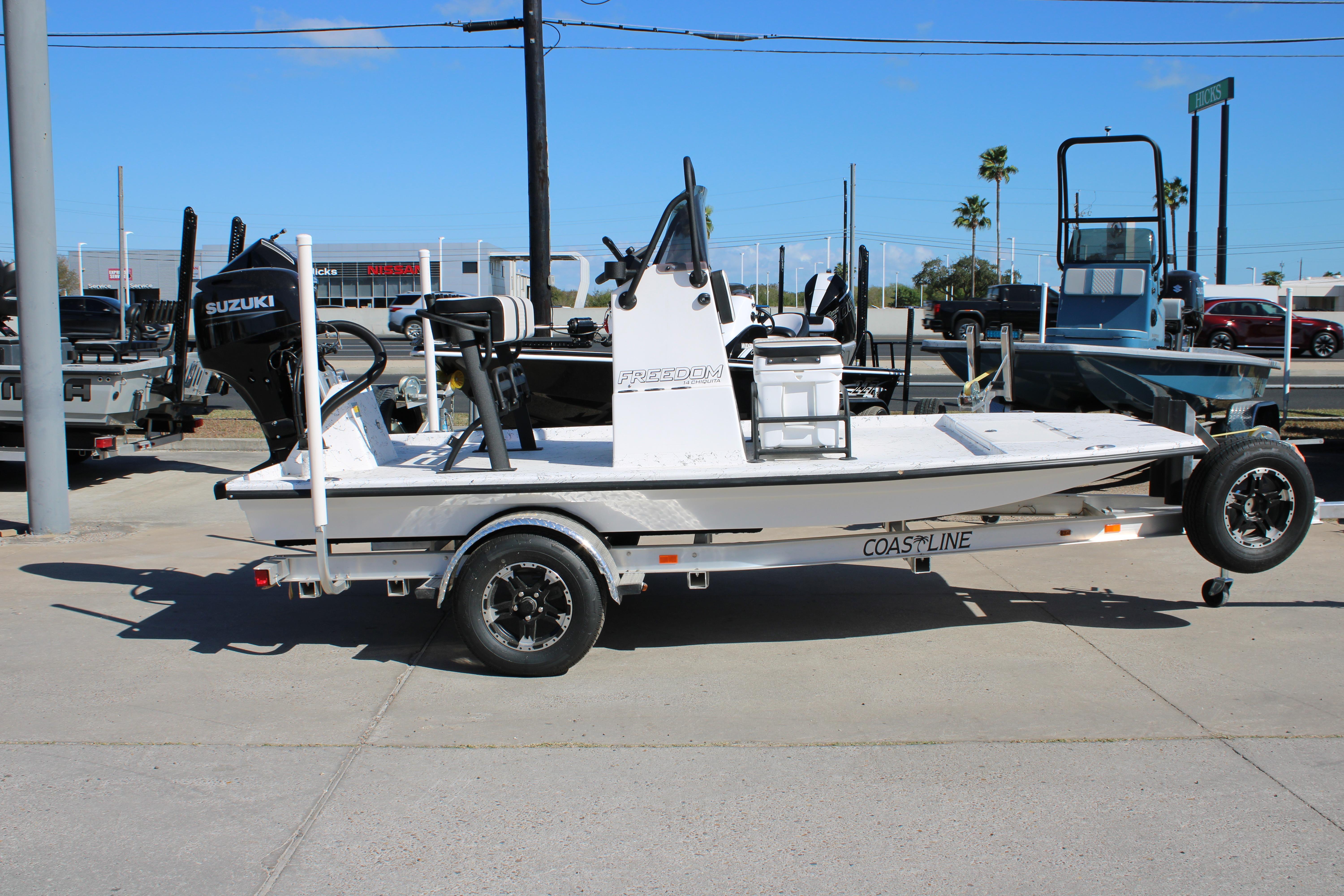 2026 Freedom Boats Chiquita on trailer, featuring Suzuki outboard motor, parked outdoors.