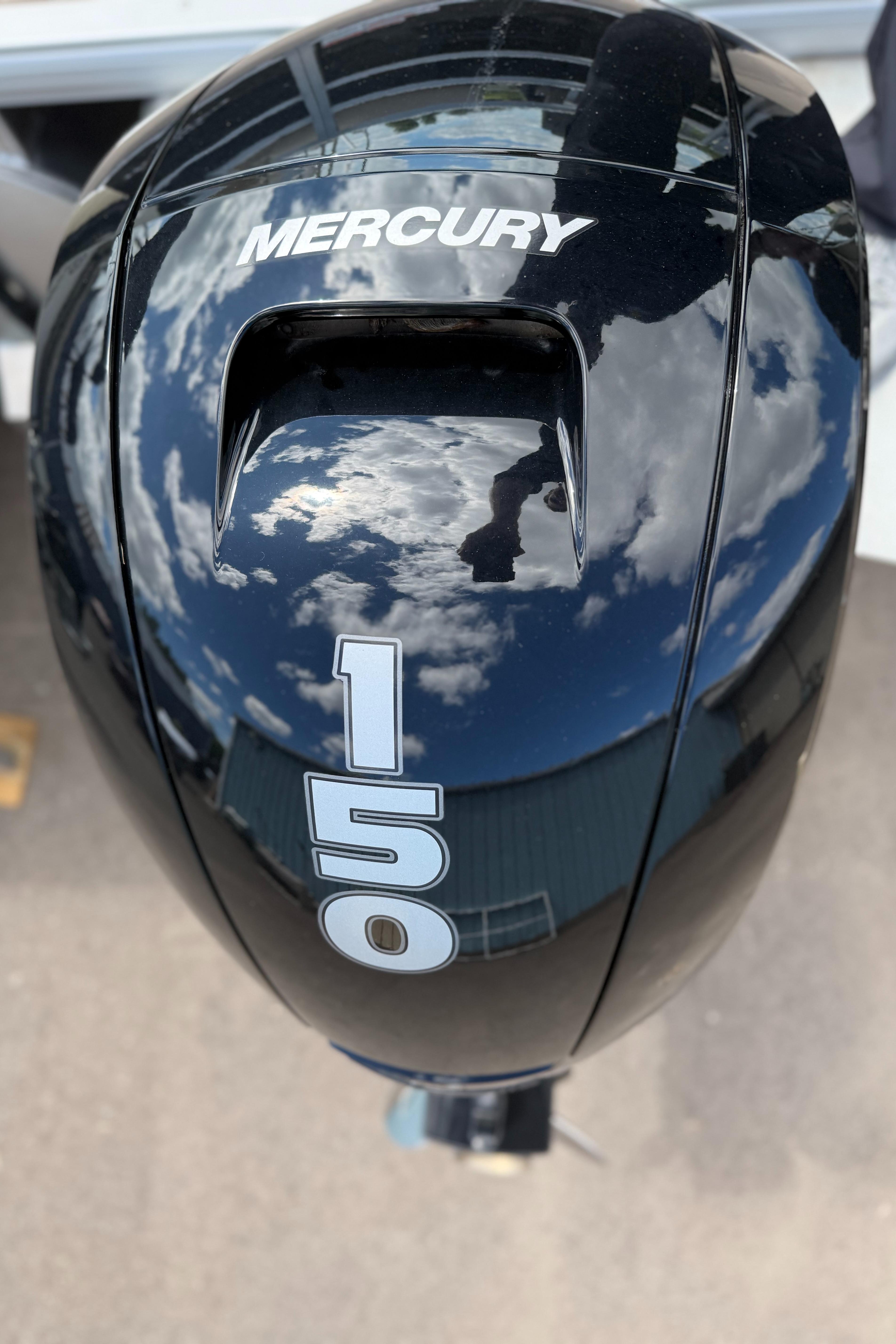 Mercury 150 outboard motor on 2024 Sun Tracker Sportfish 24 XP3, reflecting sky and clouds.