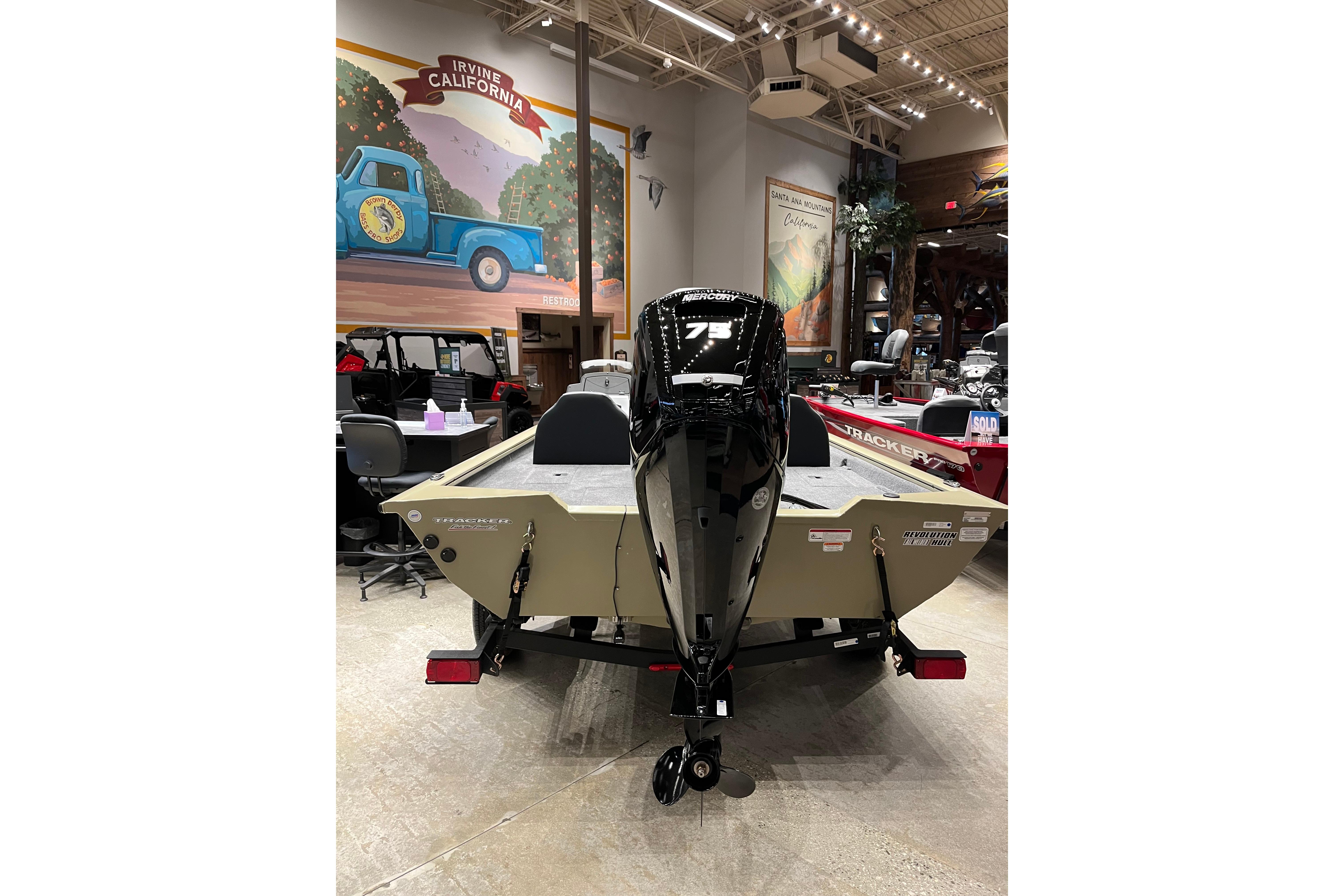2026 Tracker Pro Team 175 boat displayed indoors with motor, Irvine, California mural in background.