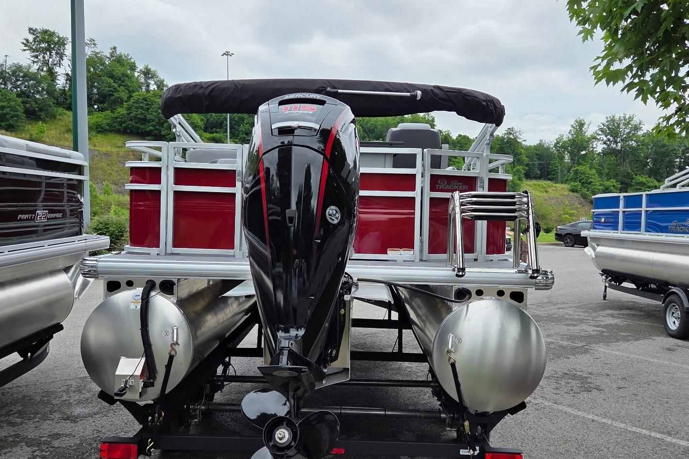 2026 Sun Tracker SportFish 20 DLX pontoon boat with powerful outboard motor, parked outdoors.
