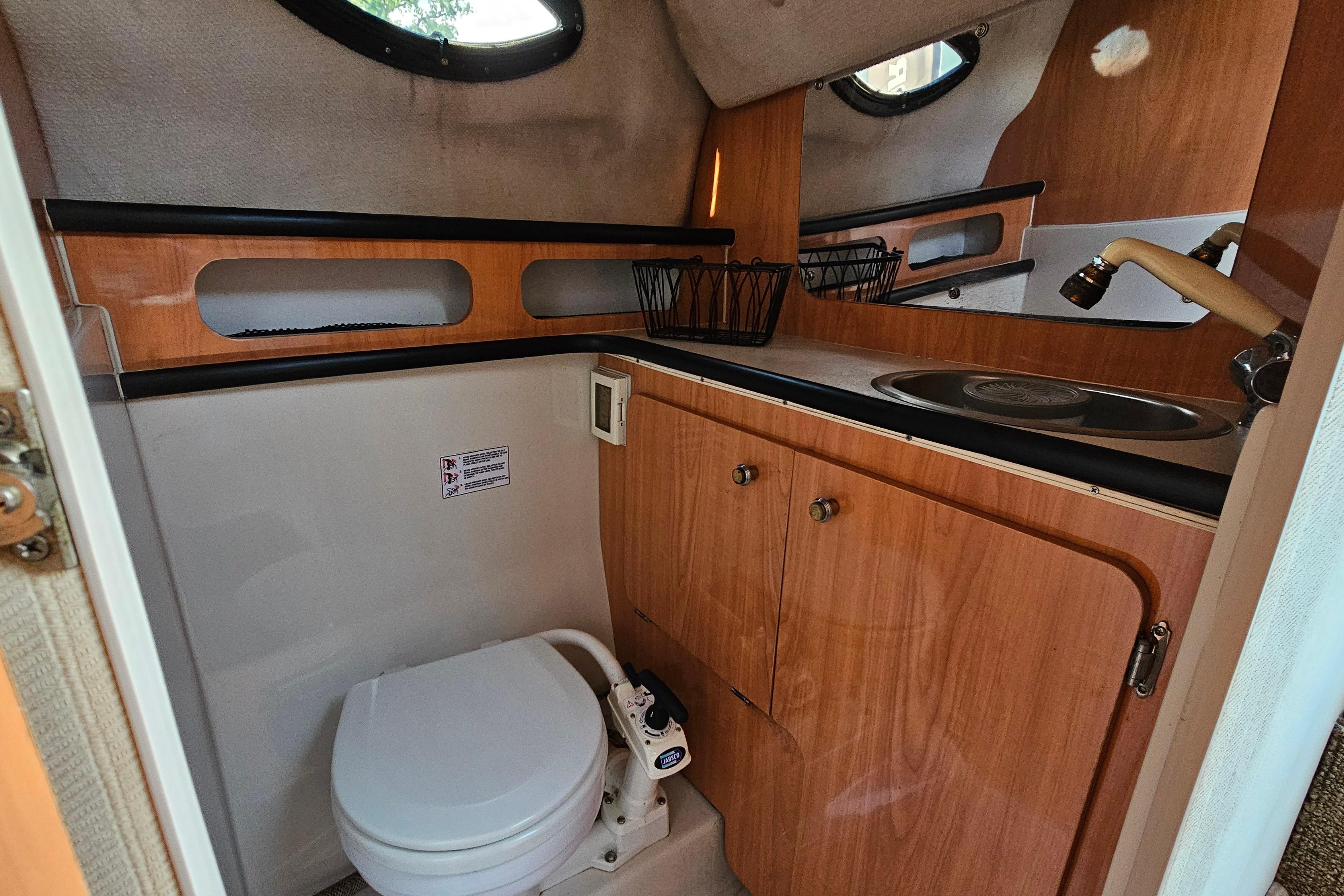 1999 Regal Commodore 258 boat interior with compact bathroom and wooden cabinetry.