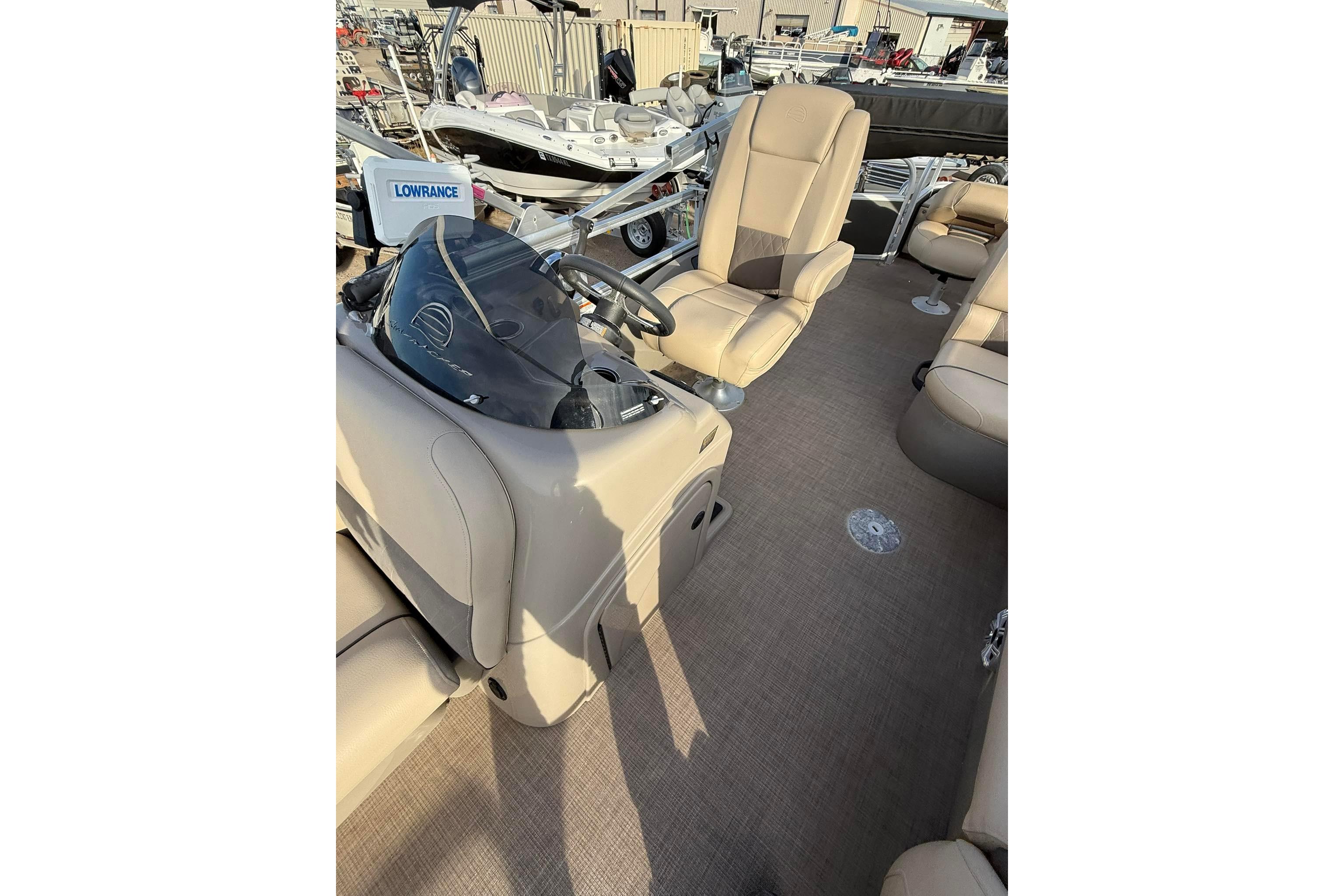 2023 Sun Tracker Fishin' Barge 22 DLX interior with beige seating and steering console.