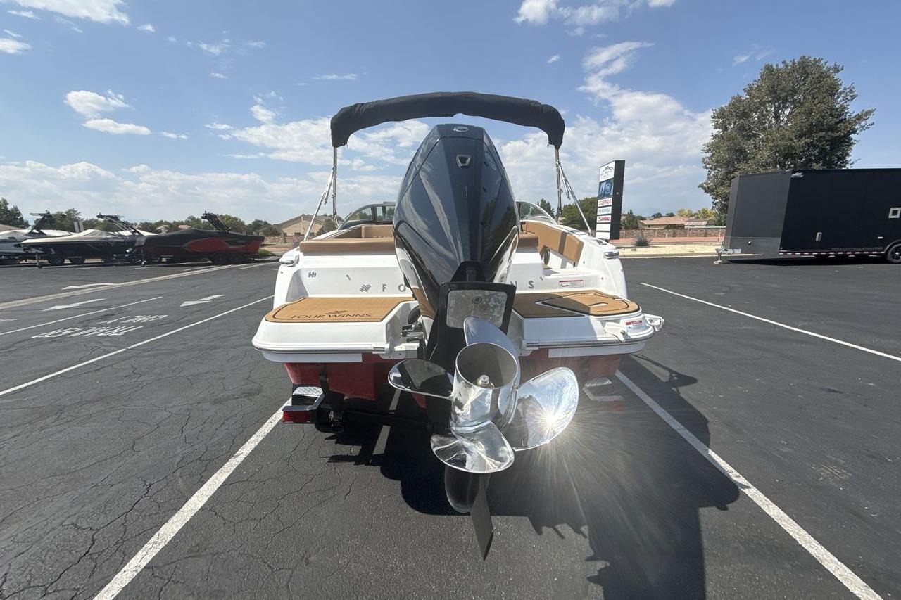 2024 Four Winns H1 OB boat, rear view with outboard motor, parked outdoors.