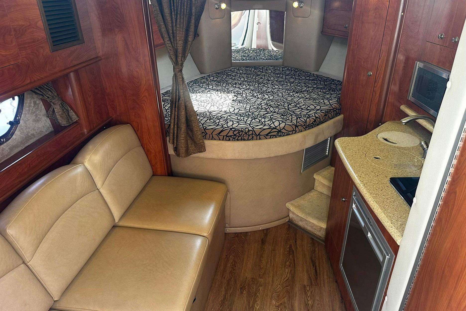 Interior of 2012 Rinker 310 Express Cruiser LE with cozy seating and compact kitchenette.