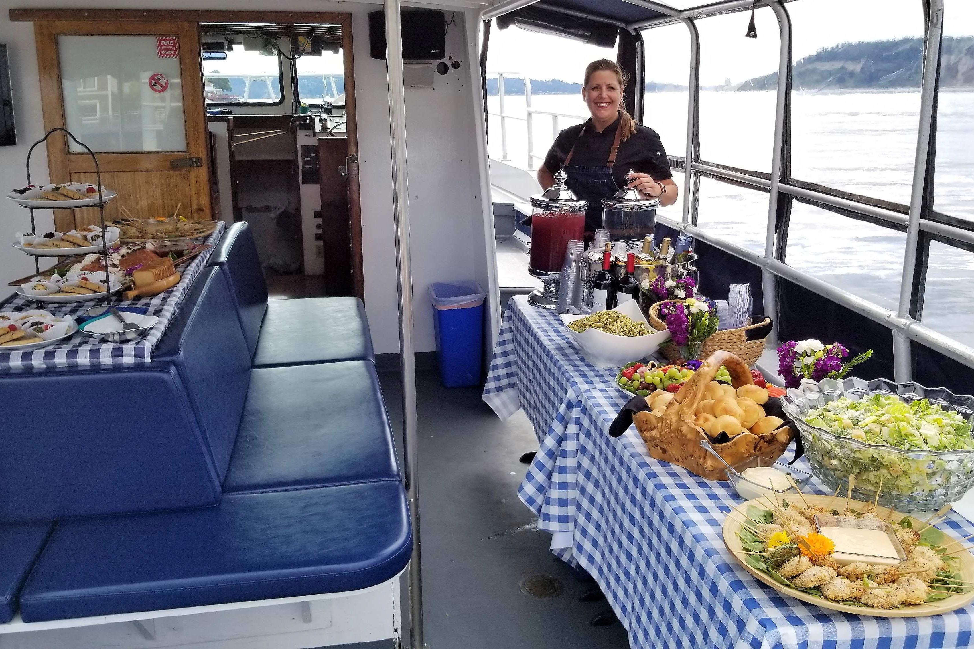 1964 Grandy Tour Boat with buffet setup, featuring assorted foods and drinks on checkered tablecloths.