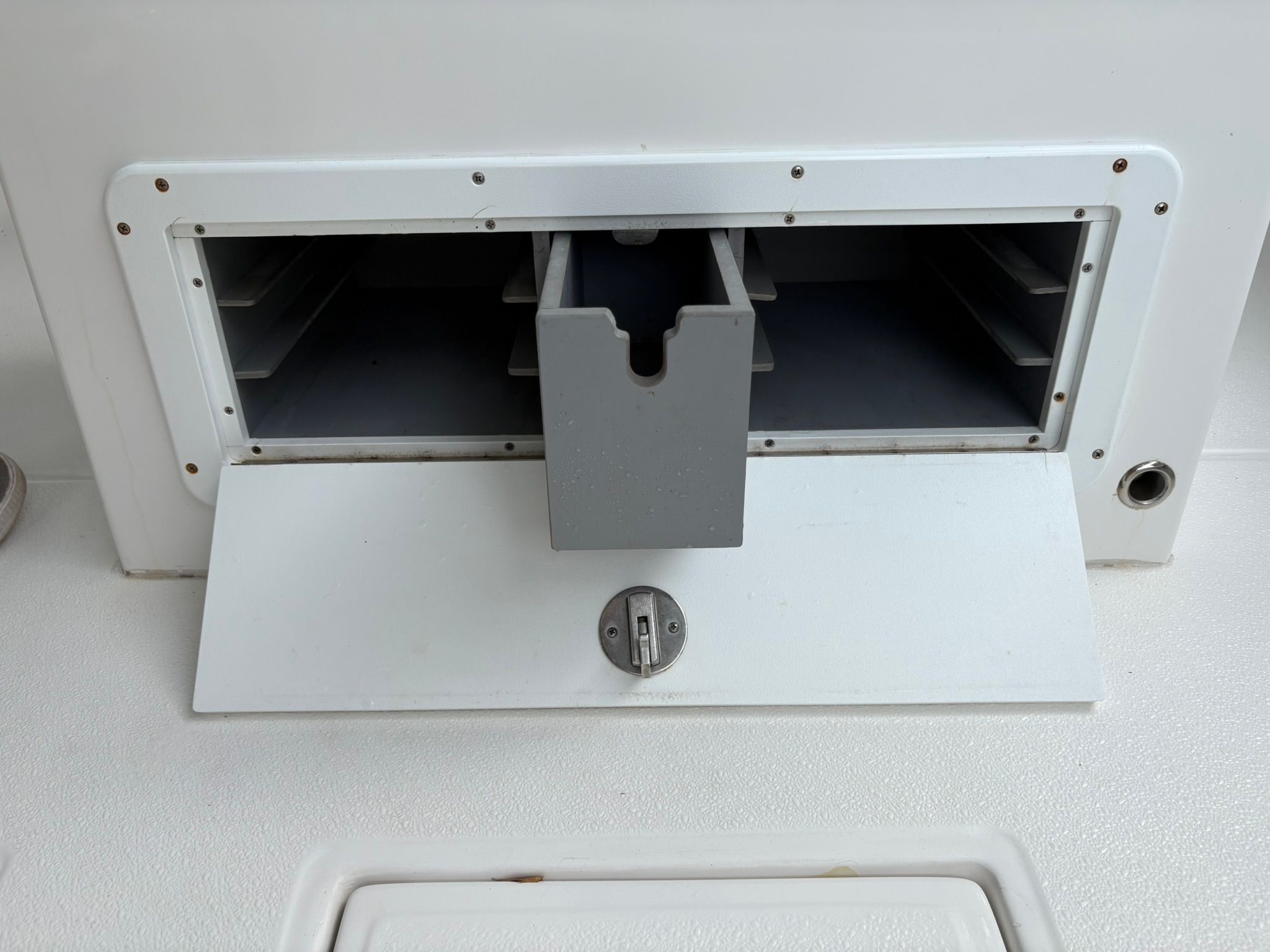 An open storage compartment on a boat with a gray insert.