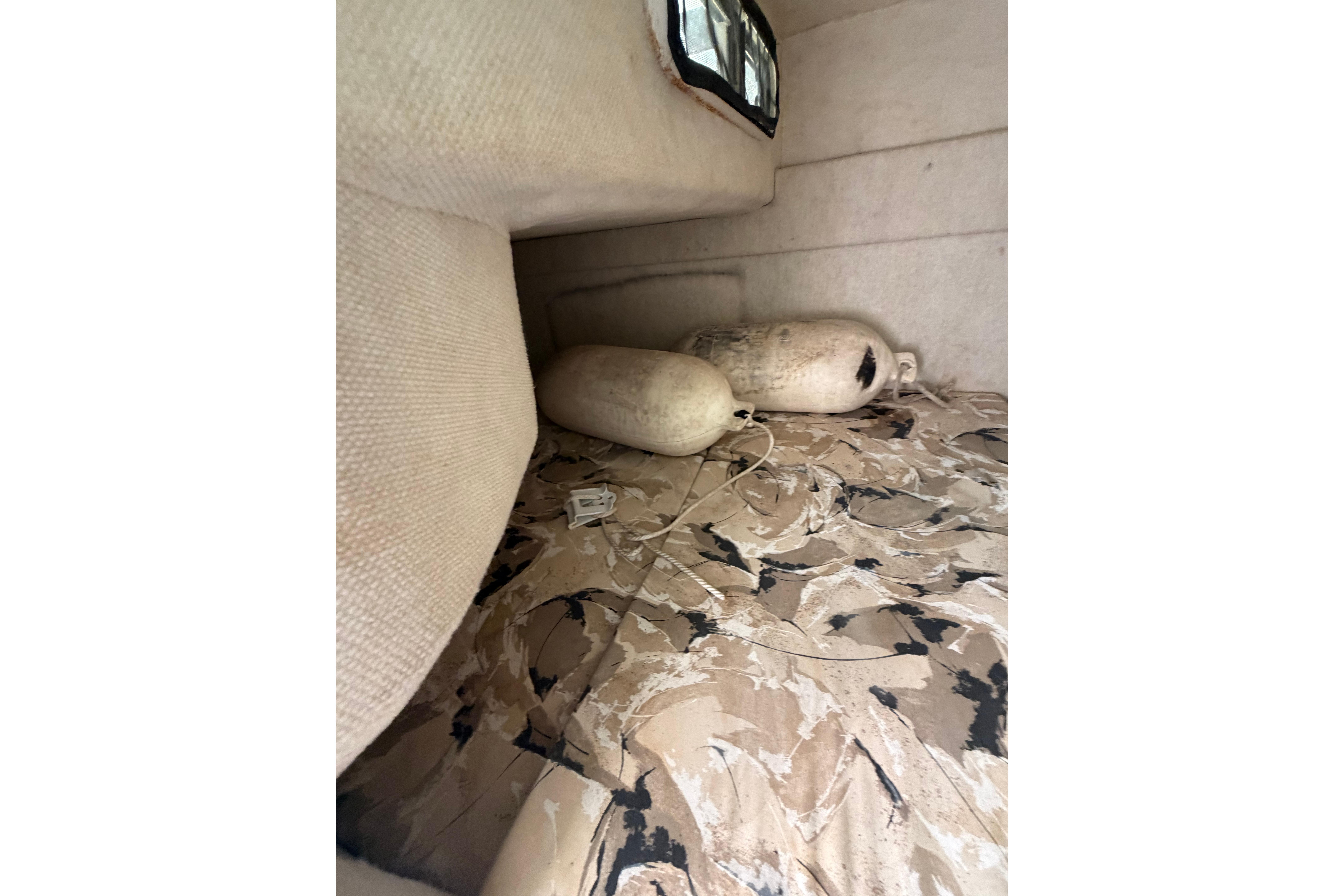 Interior cabin of 1999 Sea Ray 240 Sundancer with patterned upholstery and boat fenders.