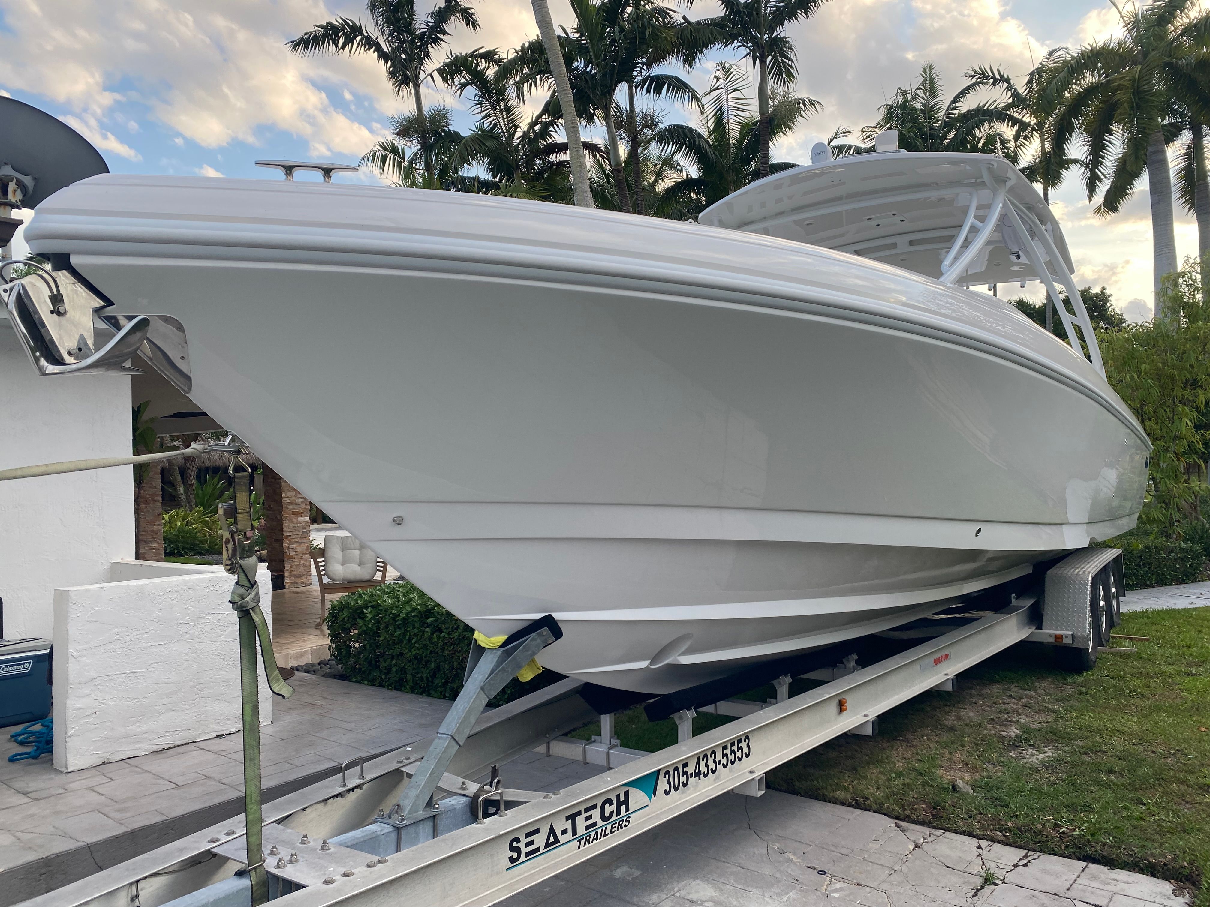A 2011 Intrepid 37 boat on a trailer, surrounded by palm trees.