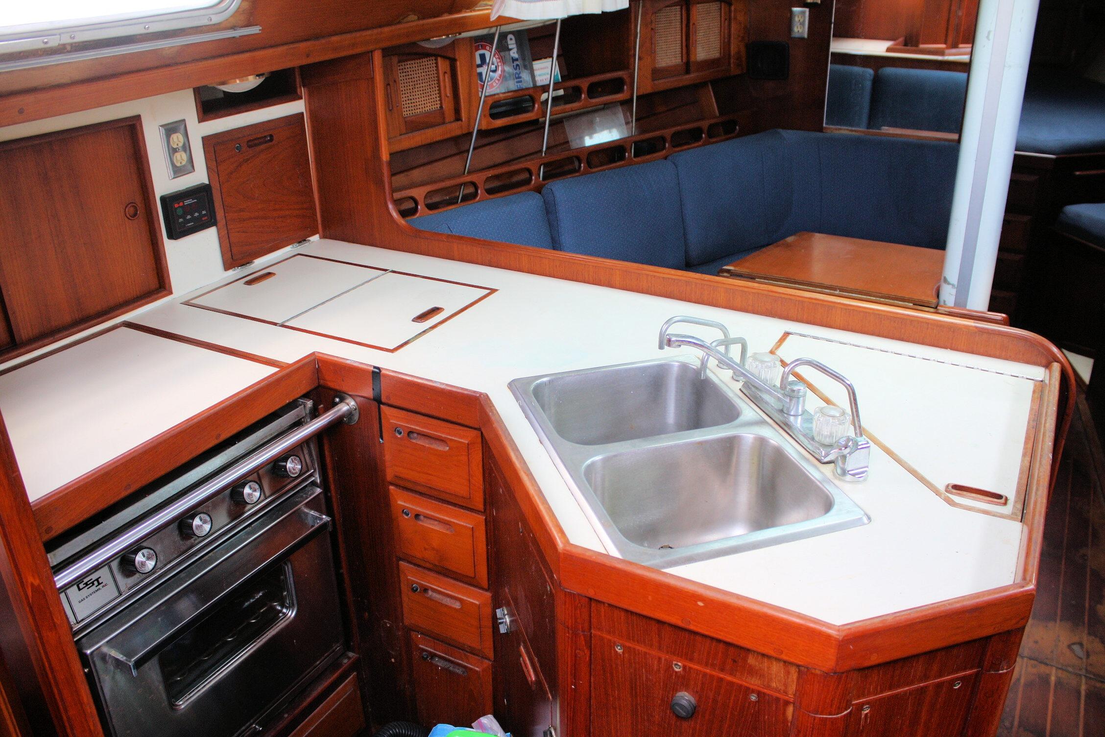 1987 Ericson 38-200 yacht interior with wooden cabinetry, dual sink, and stove in the galley.