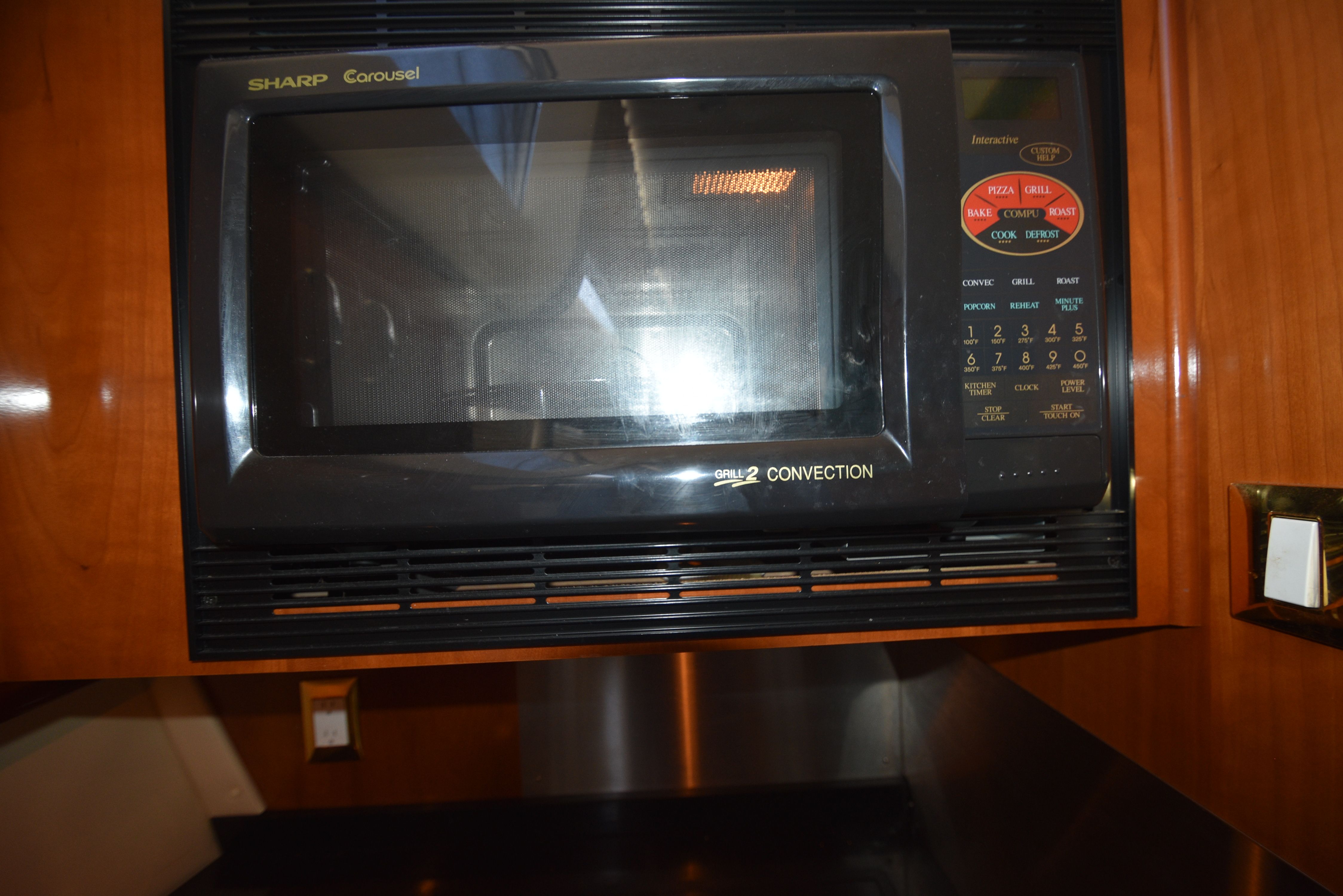 A microwave oven in a yacht kitchen, surrounded by wooden cabinetry.