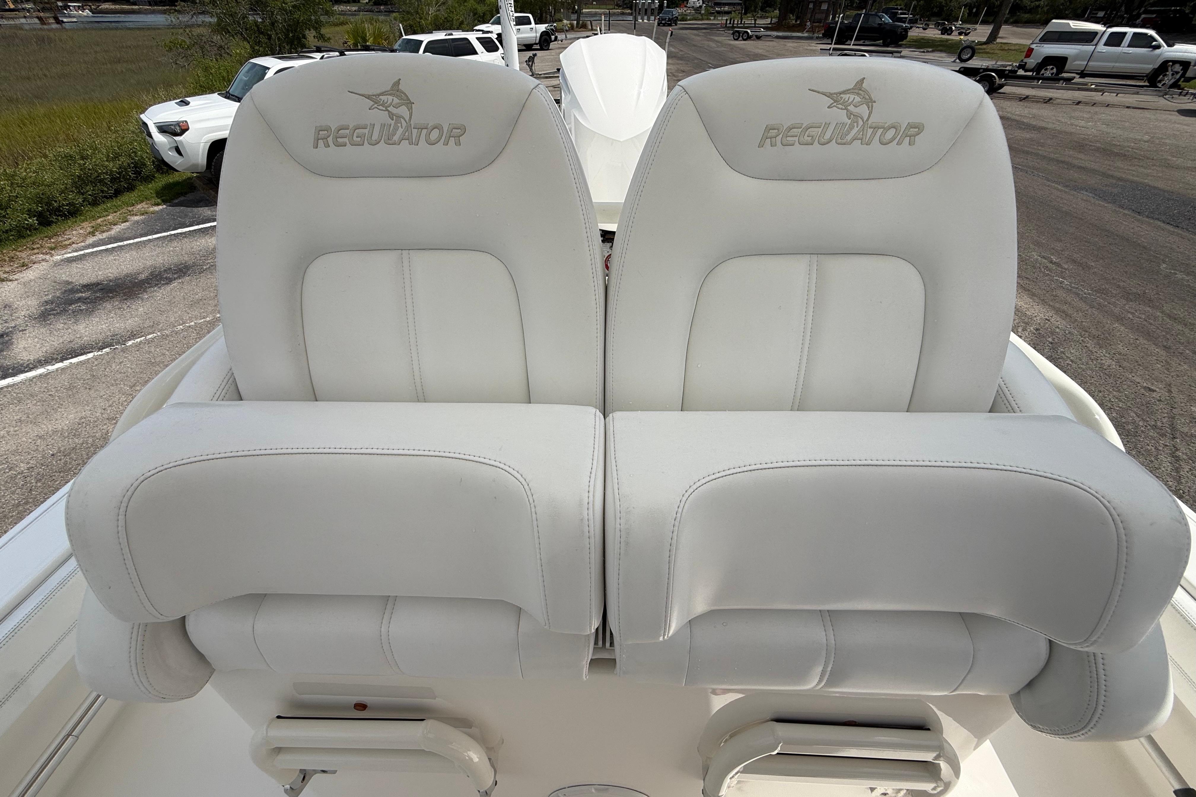 2019 Regulator 26XO boat seats, white leather, logo embossed, parked outdoors.