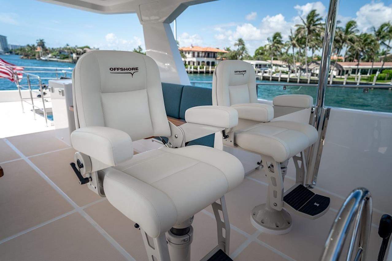 Luxury seating on 2027 Offshore Yachts 70 CE, overlooking serene waterfront views.