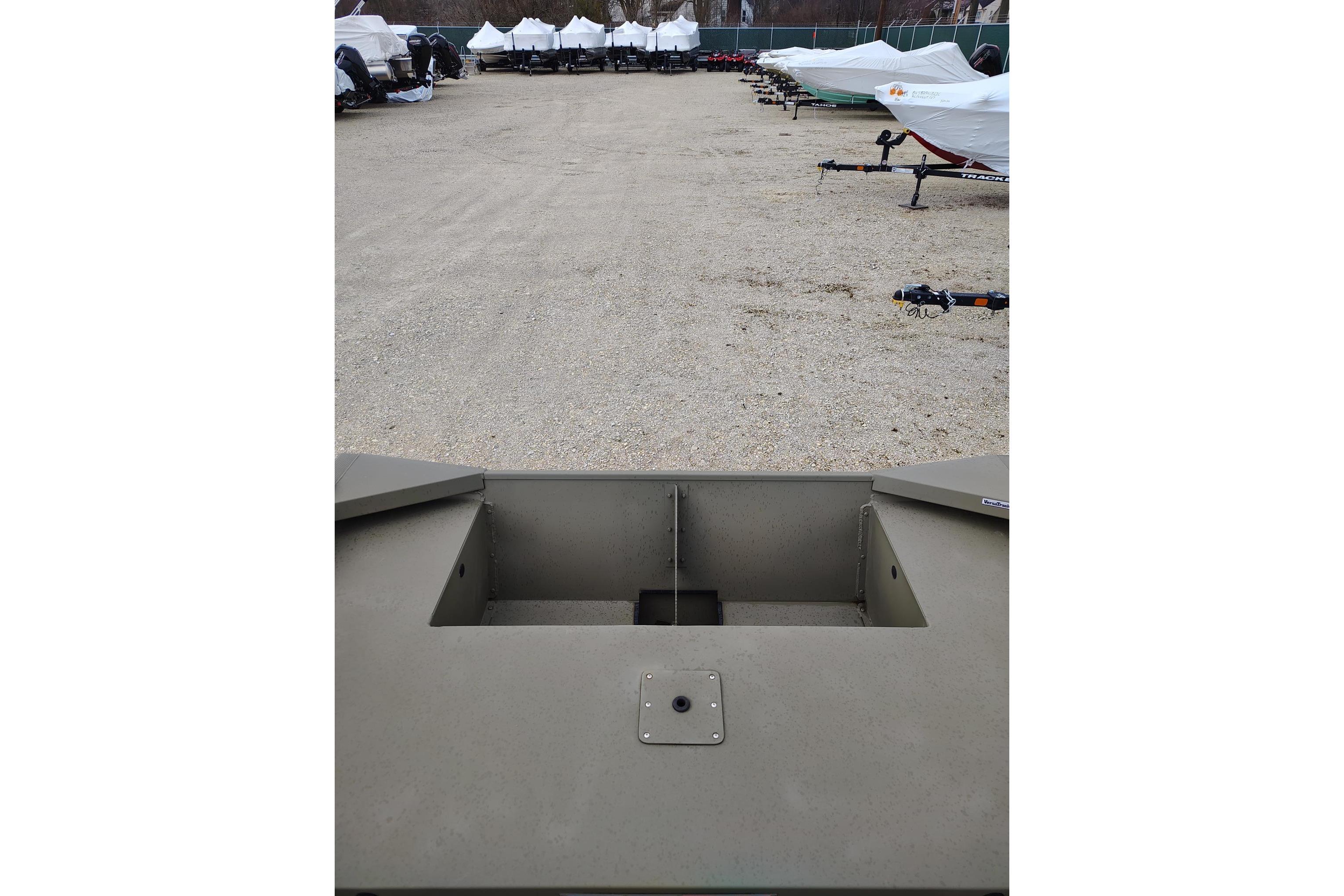 2025 Tracker Grizzly 1860 Utility boat in a storage yard with covered trailers.