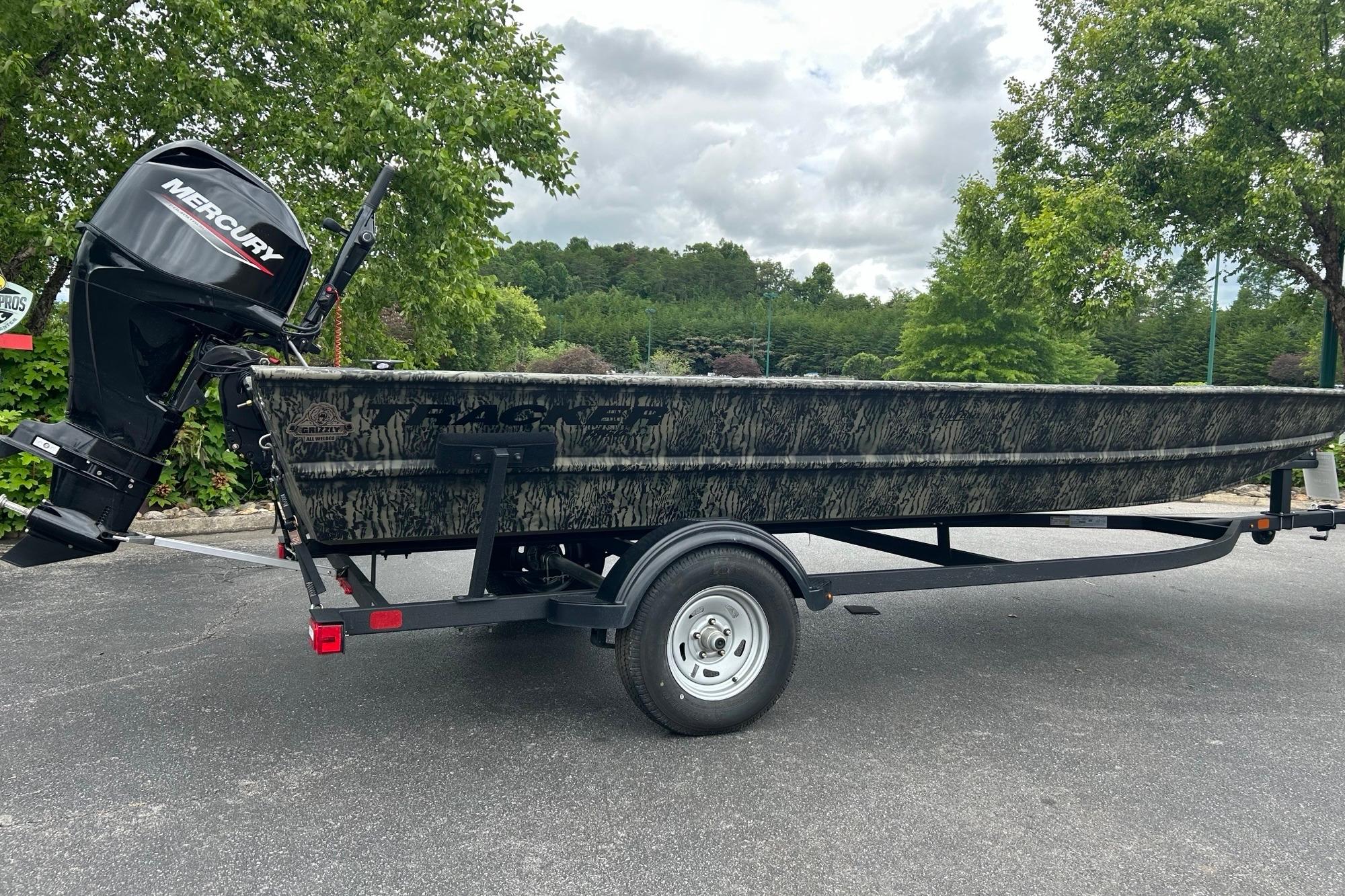 2025 Tracker Grizzly 1860 AWL boat with Mercury engine on trailer, parked outdoors.