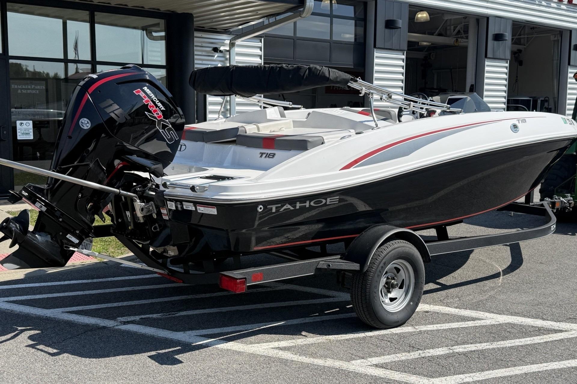 2024 Tahoe T18 boat on trailer with Mercury engine, parked outside dealership.