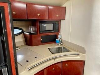 2001 Wellcraft Martinique 3700 yacht kitchen with microwave, sink, and wooden cabinets.