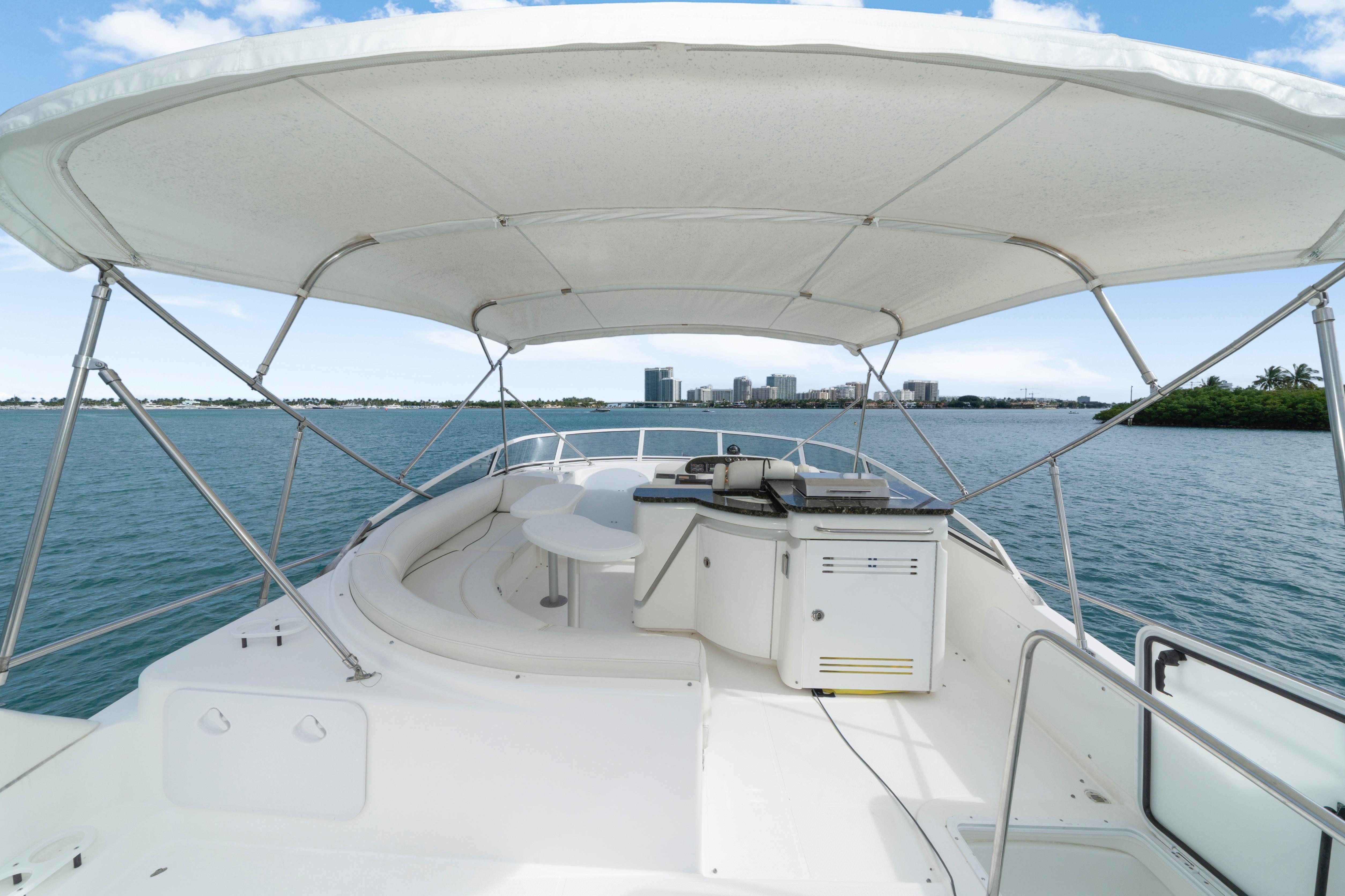 2001 Cruisers Yachts 5000 Sedan Sport with canopy, overlooking serene waters and distant cityscape.