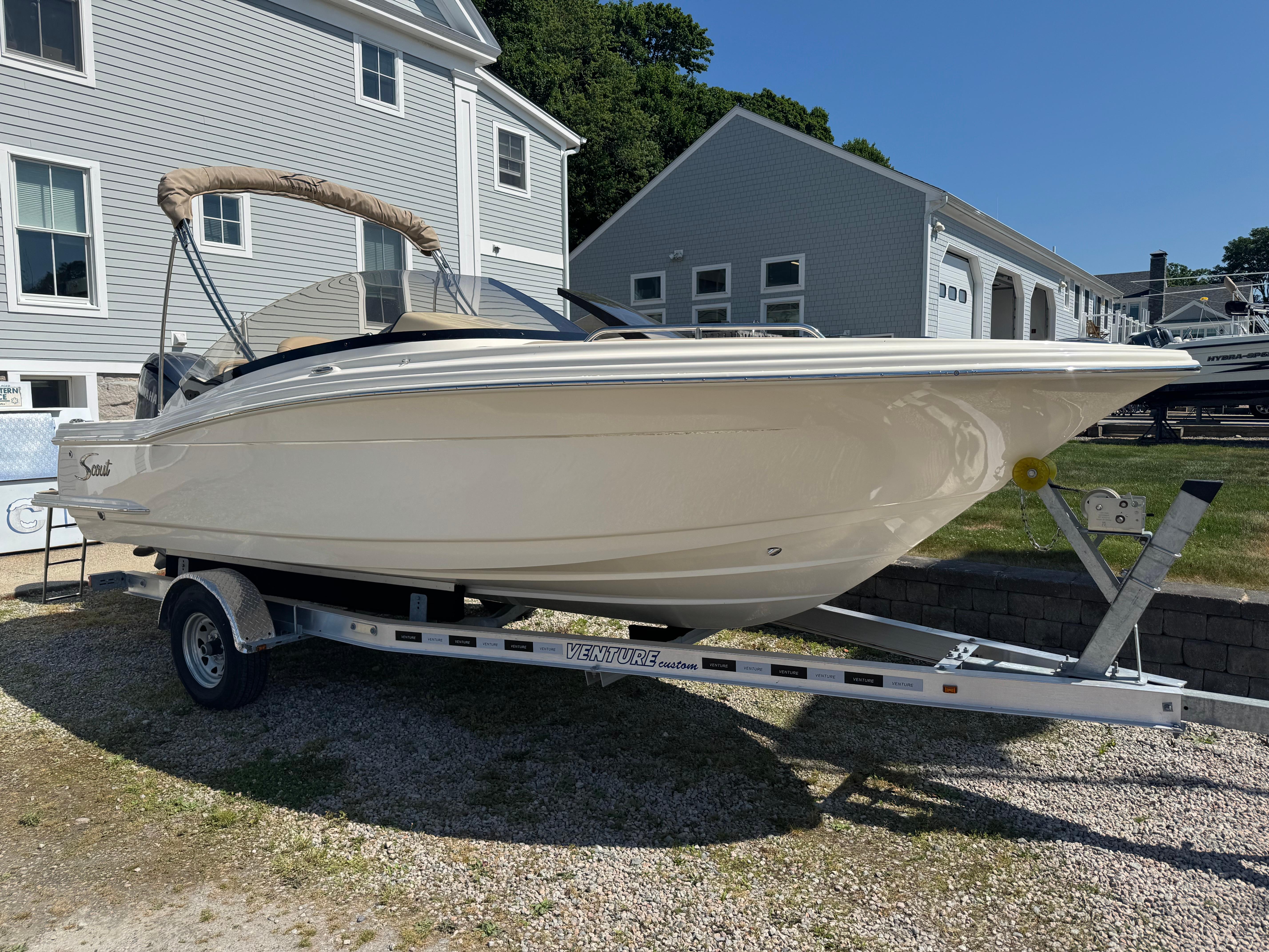 2025 Scout 215 Dorado boat on trailer, parked outdoors near buildings.