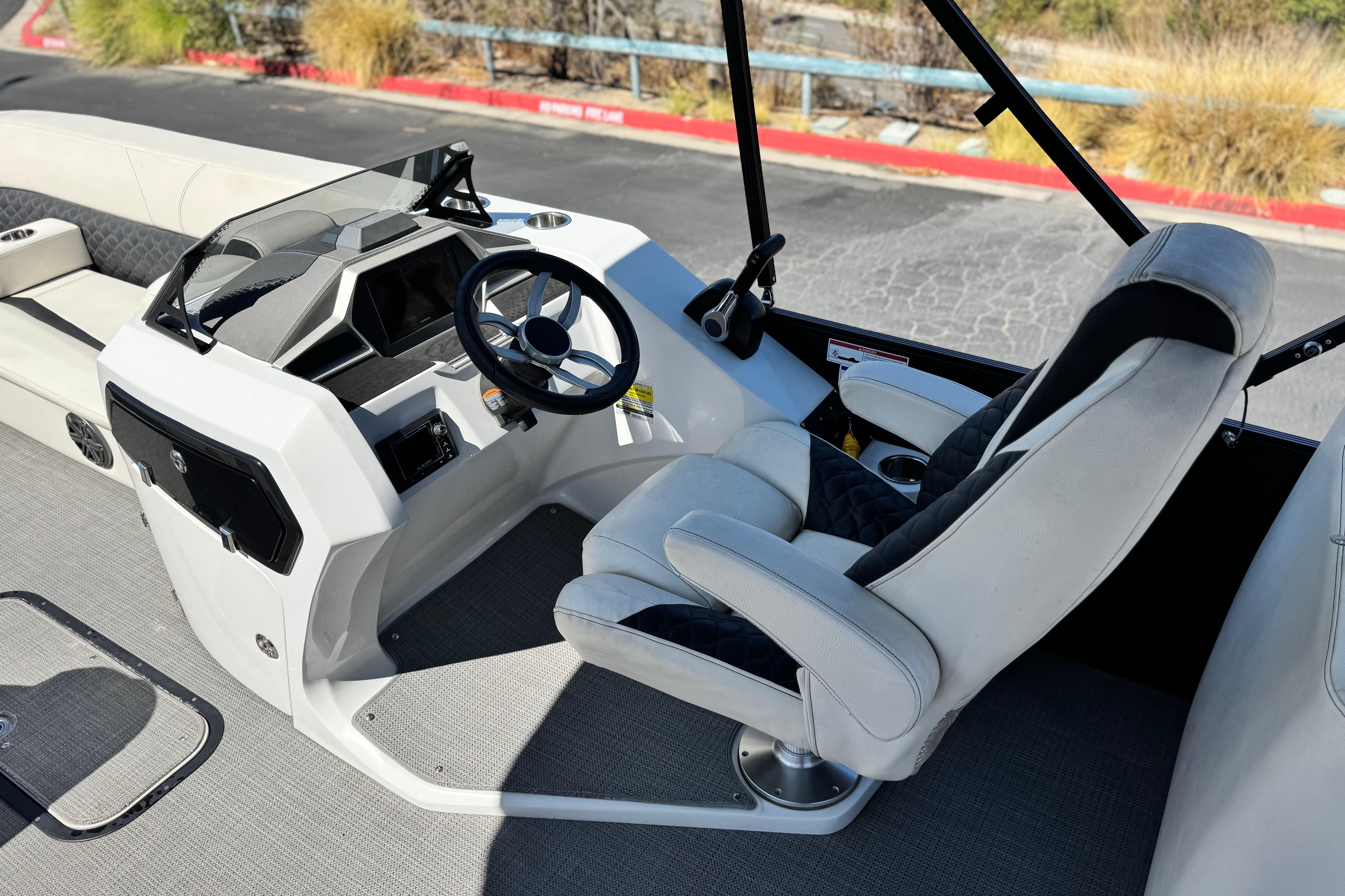 2021 Manitou 25 LX SHP boat interior with steering wheel and captain's chair.
