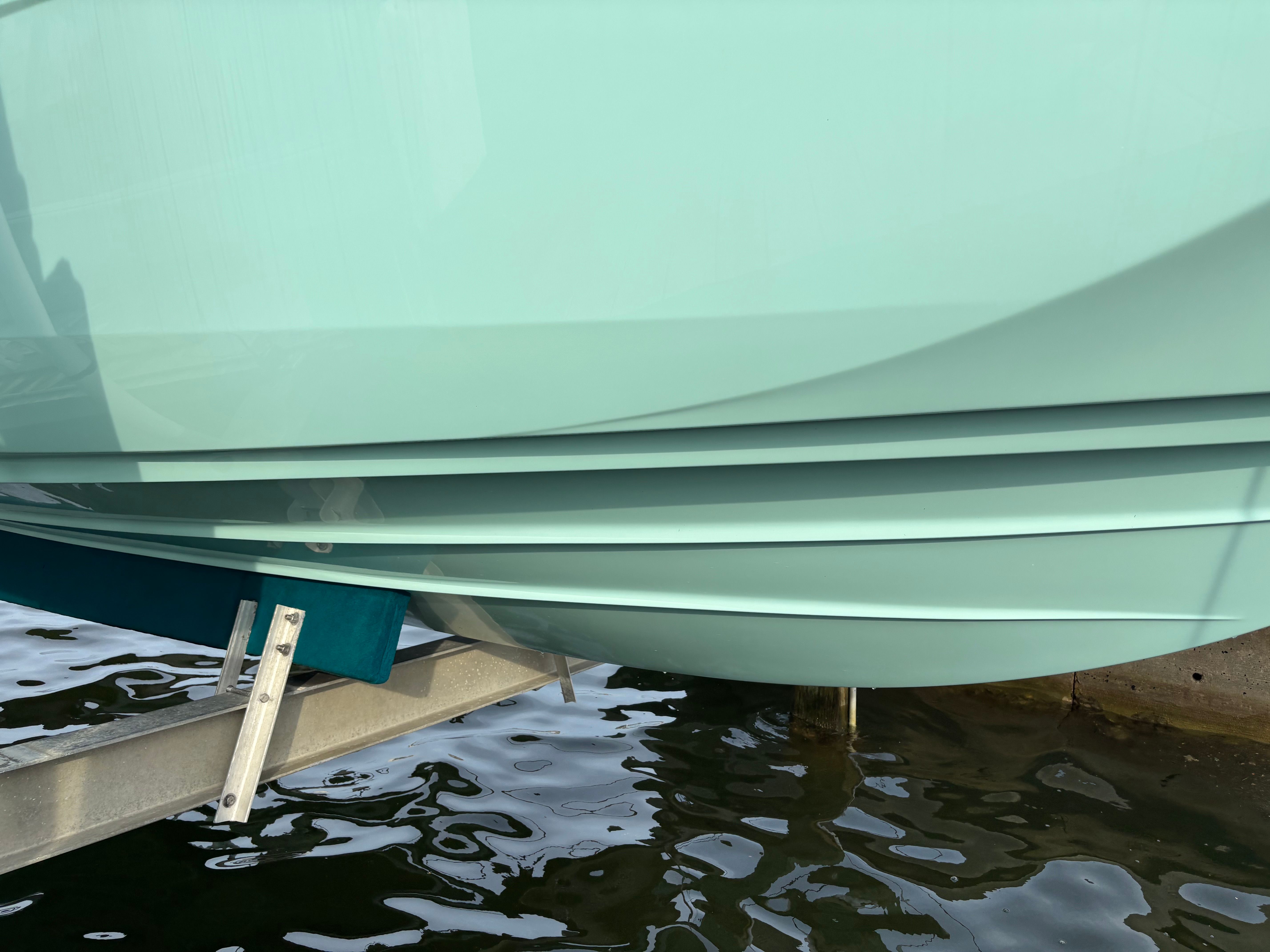 A Yamaha AR250 boat hull above the water on a boat lift.