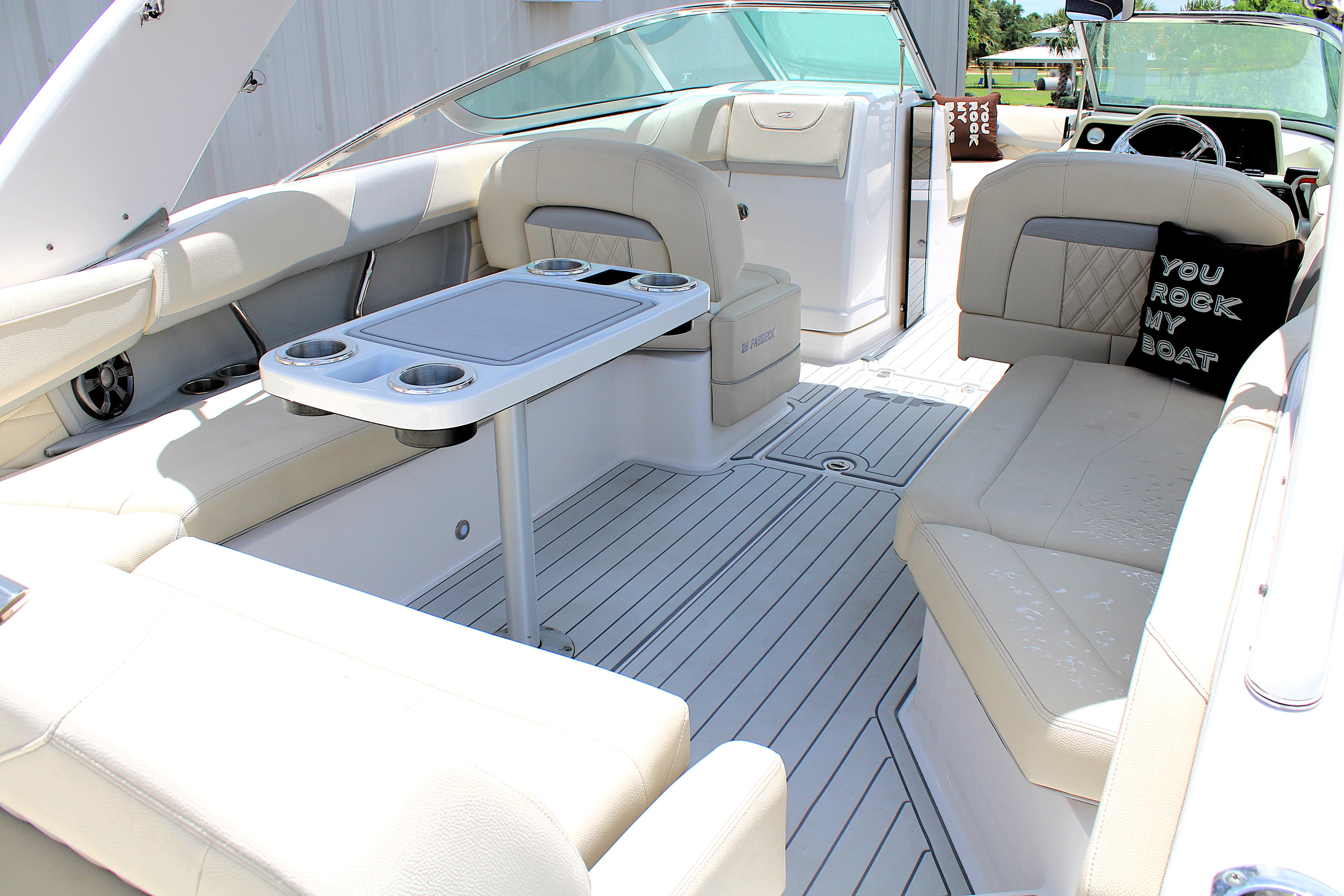 2021 Regal 26 OBX boat interior with beige seating and table, featuring a decorative pillow.