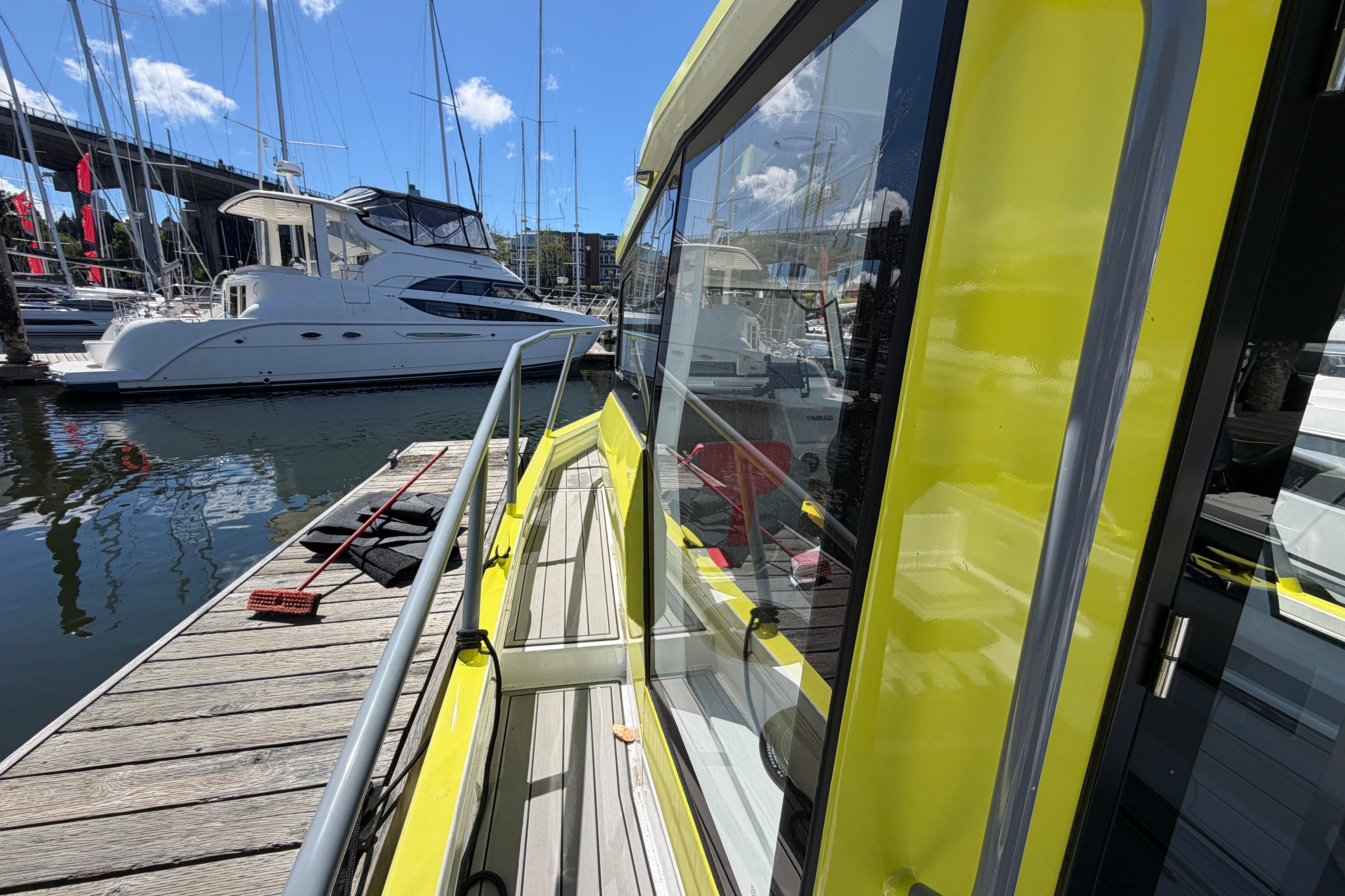 Yellow Blackfish E750w boat docked at marina, 2023 model, with yachts in background.