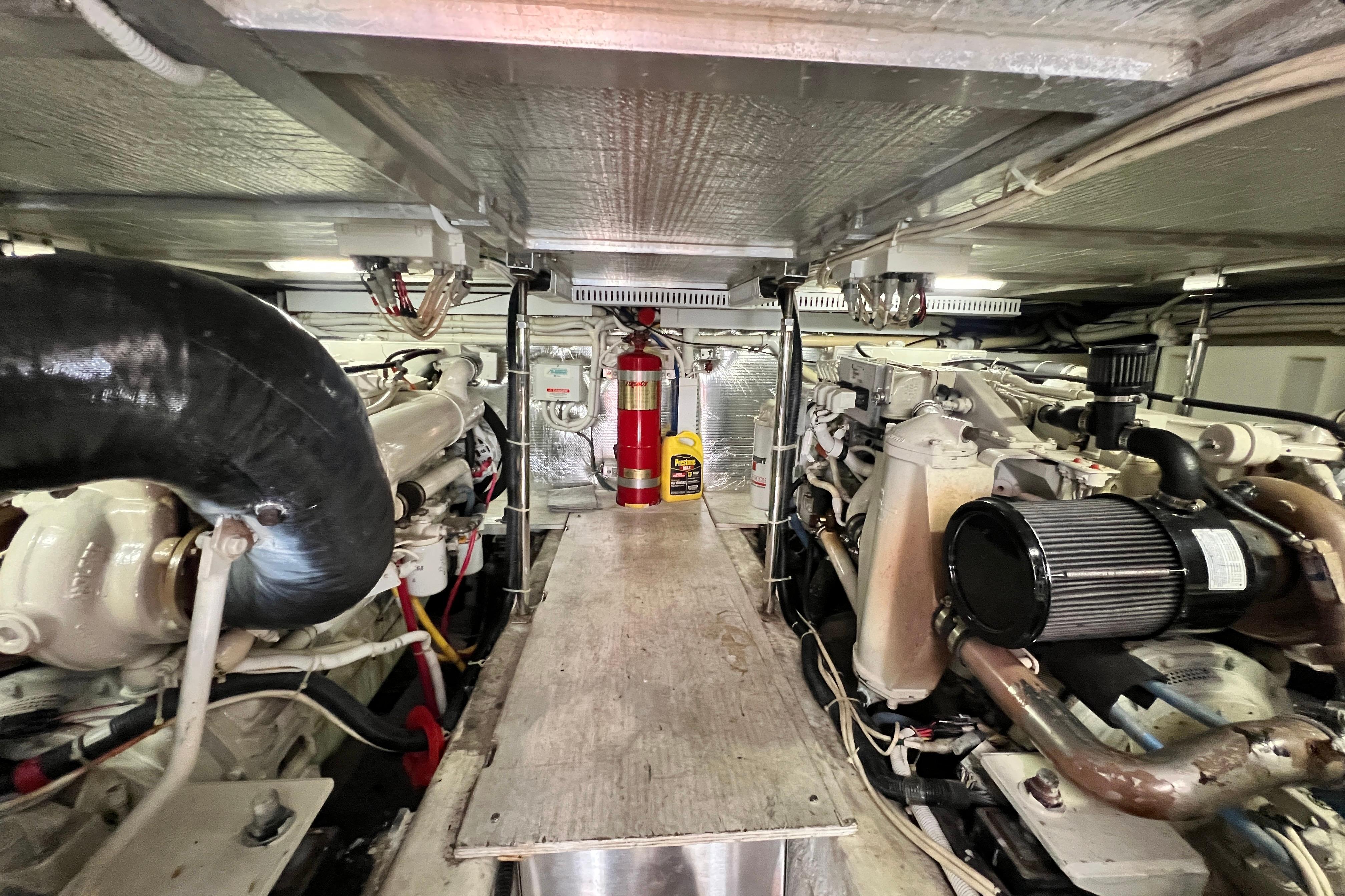 Engine room of a 2003 Carver 450 Voyager Pilothouse with visible machinery and fire extinguisher.