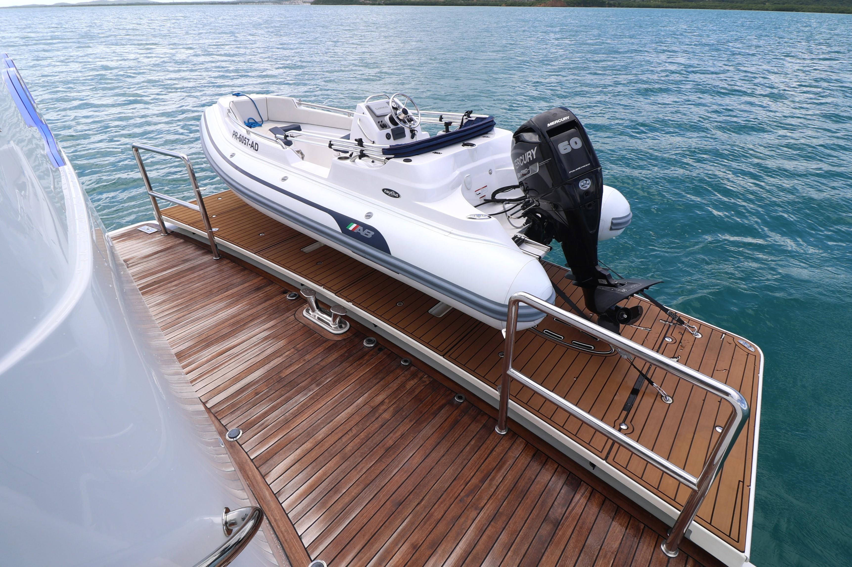 2013 Cheoy Lee Bravo yacht with tender on wooden deck, ocean backdrop.