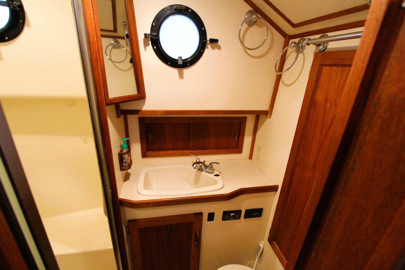Bathroom interior of 2002 Nordic Tug 37 with sink, mirror, and porthole window.