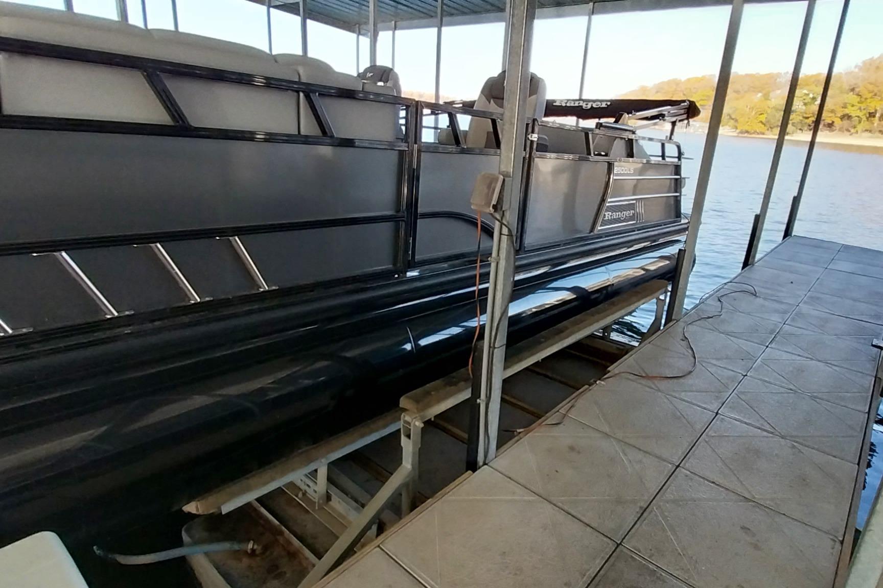 2023 Ranger 2500LS pontoon boat docked on a lake under a covered structure.