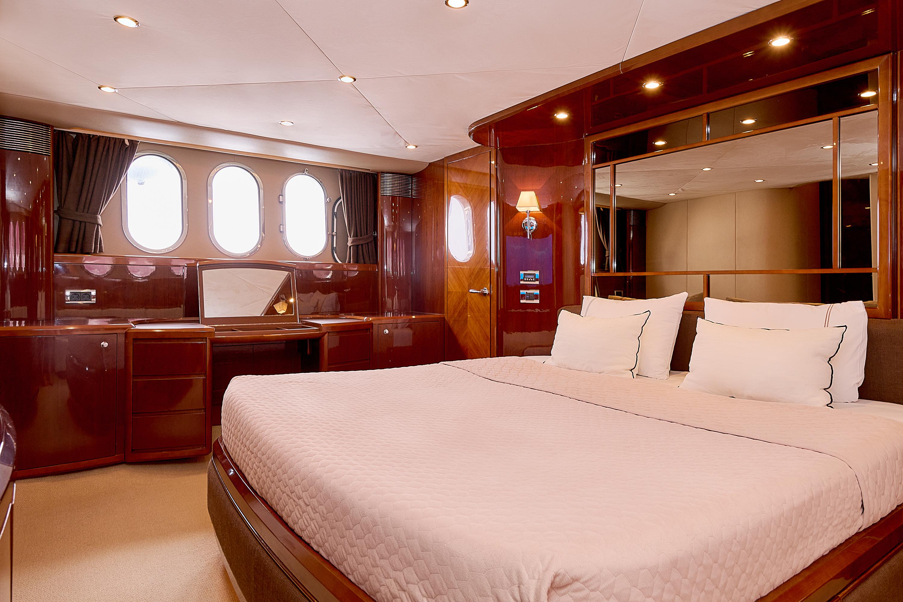 Luxurious yacht bedroom with elegant wood finish, large bed, and porthole windows, Princess 23M 2009.