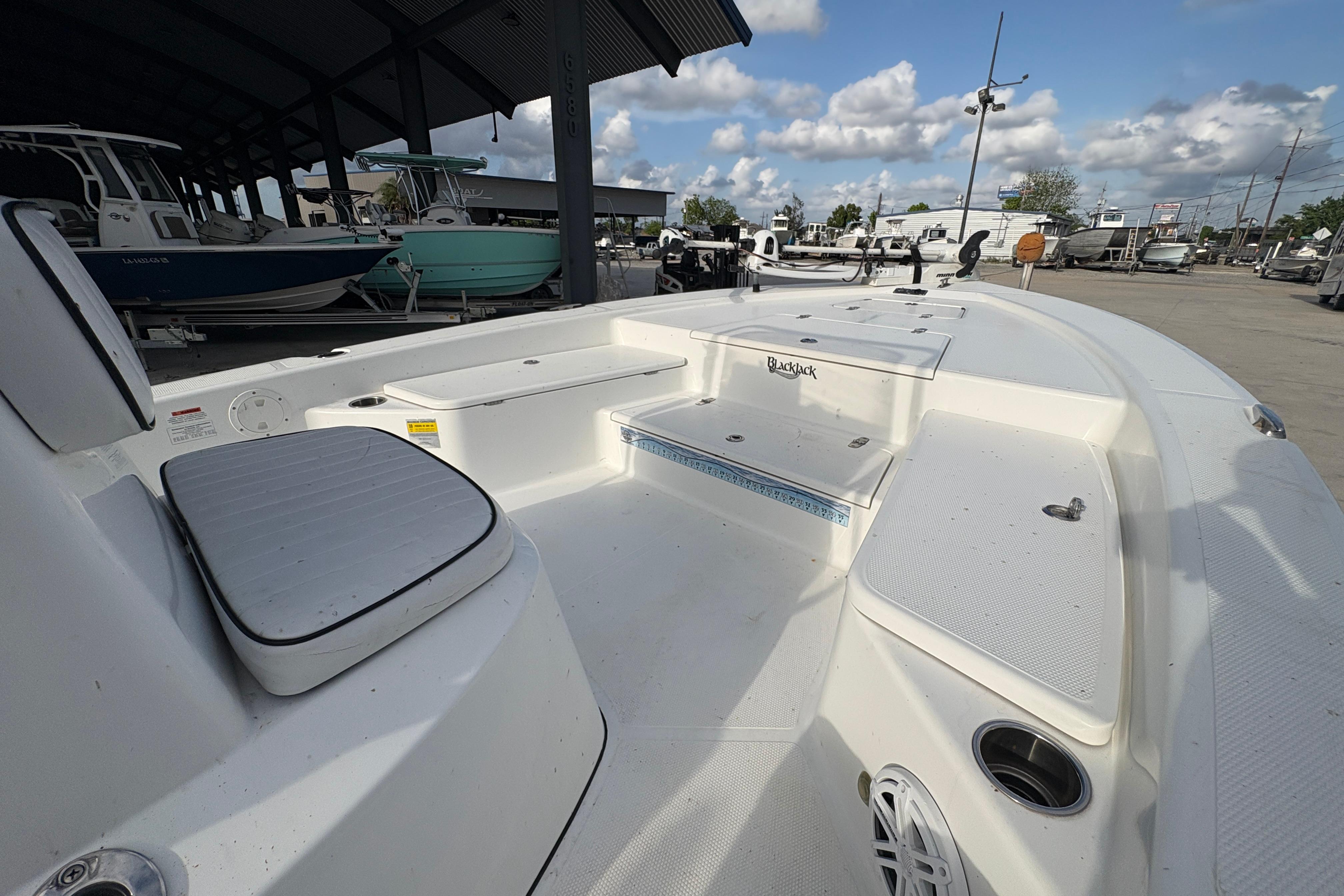 2012 BlackJack 224 boat interior with seating and storage, displayed in a marina setting.