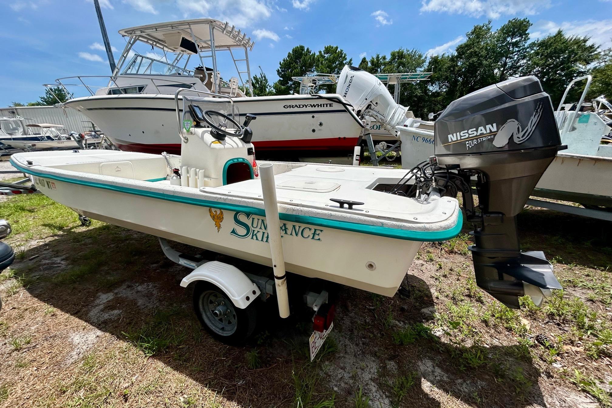 2002 Sundance K16CC boat with Nissan outboard motor, parked on a trailer.