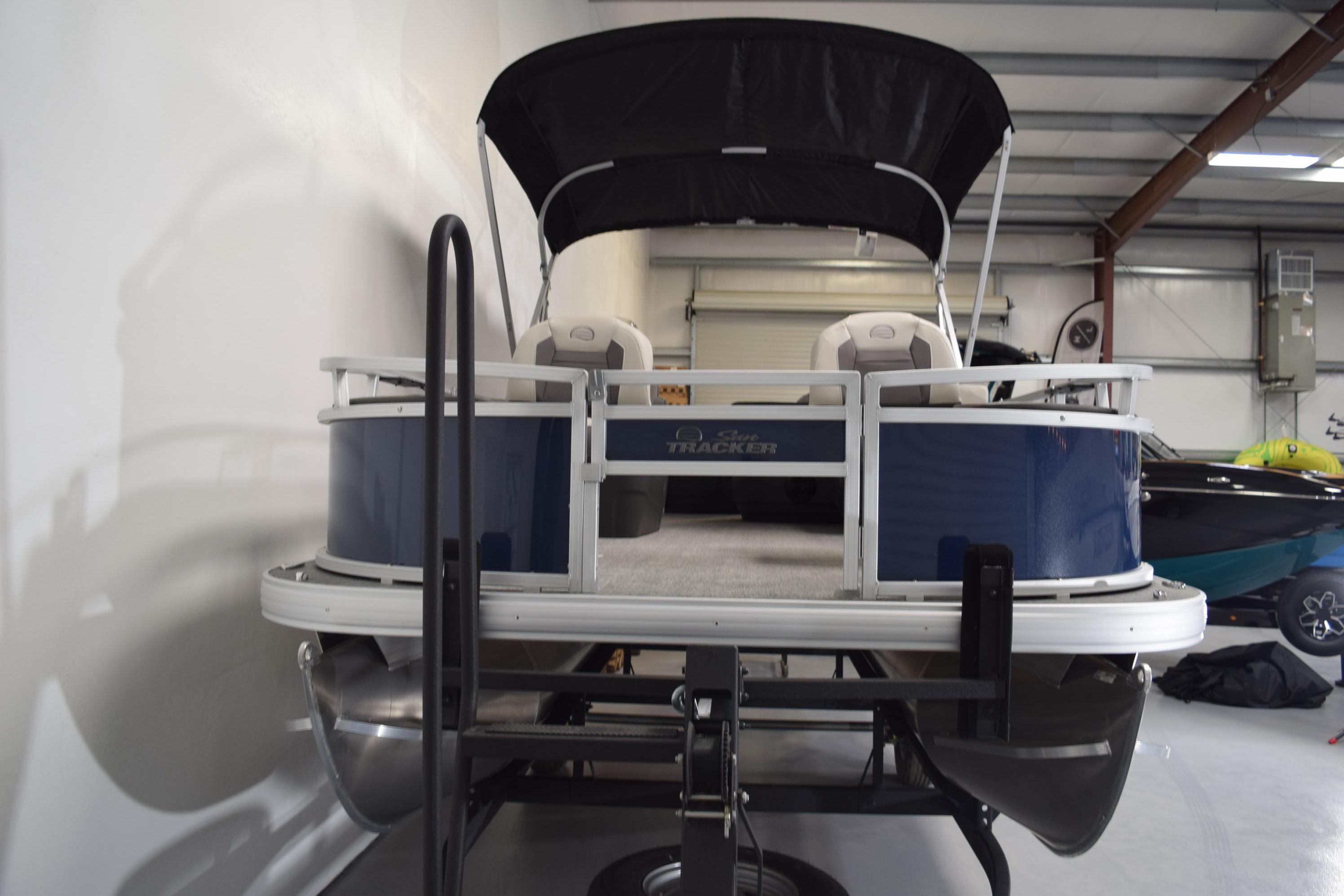 2026 Sun Tracker Bass Buggy 18 DLX pontoon boat in a garage setting.