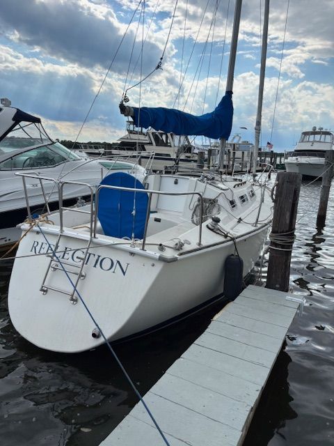 A 1988 Pearson 28 sailboat docked at a pier. The sky is cloudy.