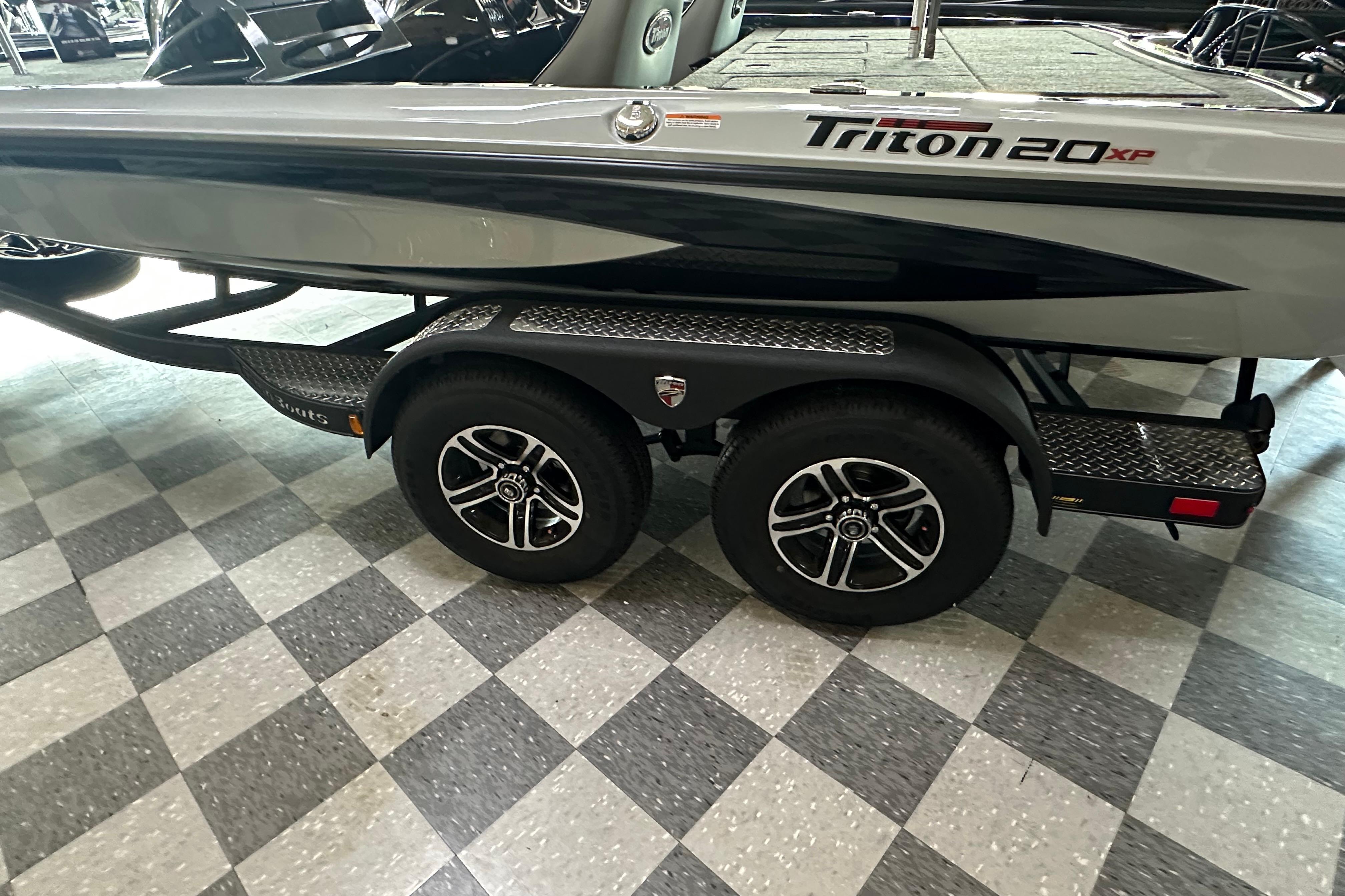 2024 Triton 20XP Patriot boat on a dual-axle trailer, displayed indoors.