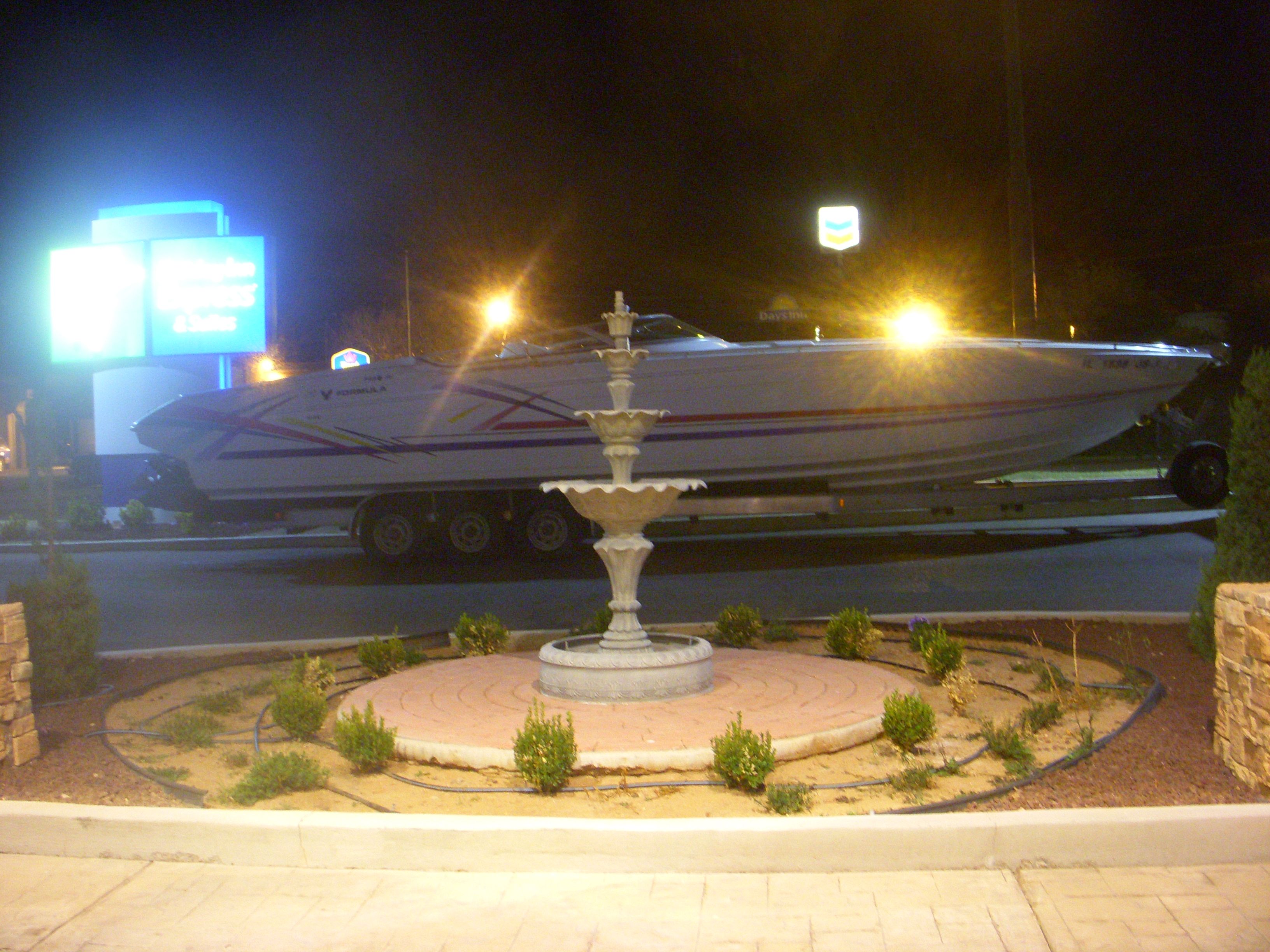1993 Formula 419 boat on trailer at night, illuminated by streetlights.