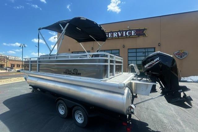 2026 Sun Tracker Fishin' Barge 20 DLX pontoon boat with Mercury engine, parked outside service center.