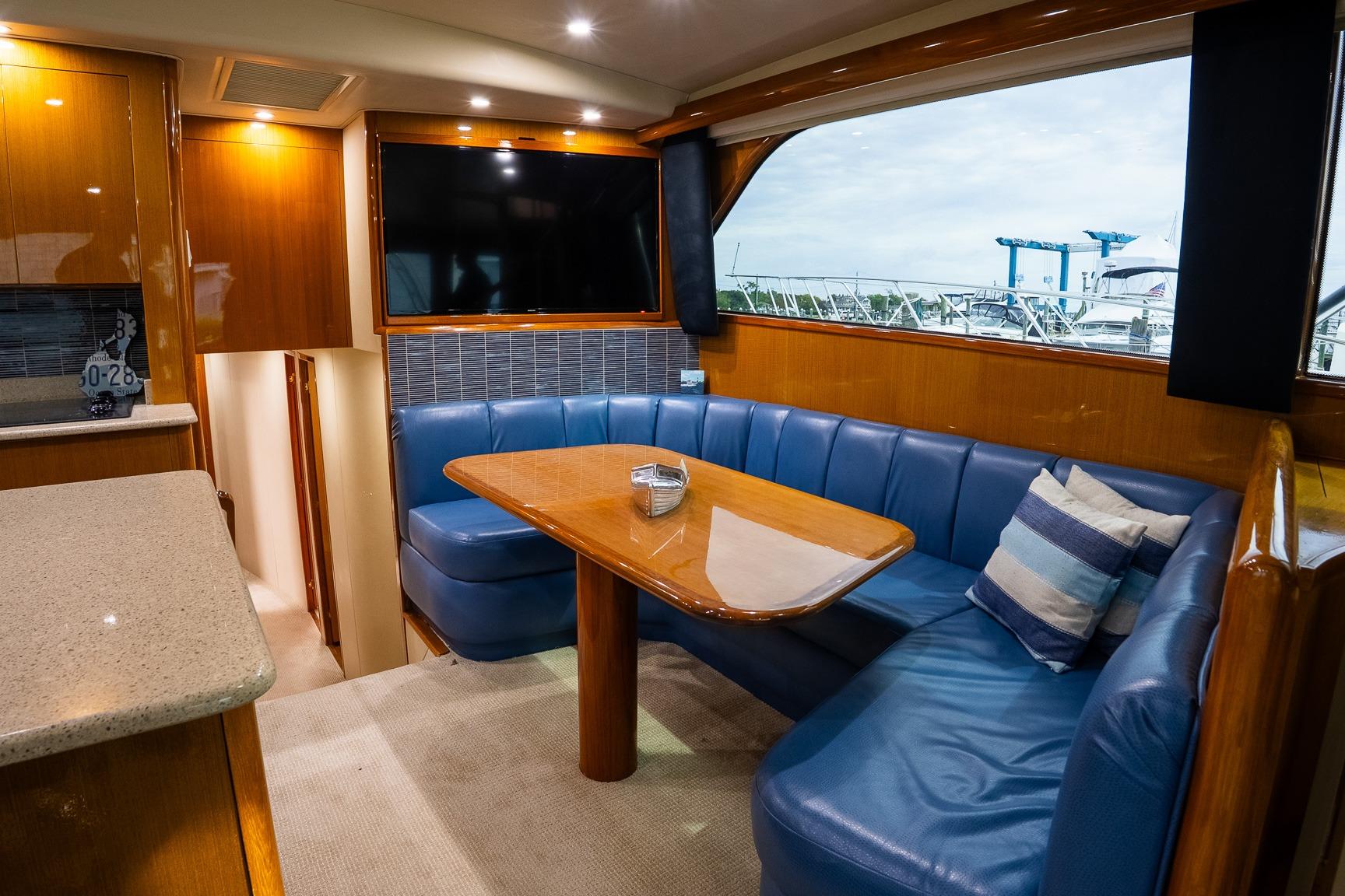 Luxurious interior of 2002 Viking 61 Enclosed Bridge yacht with blue seating and large window.
