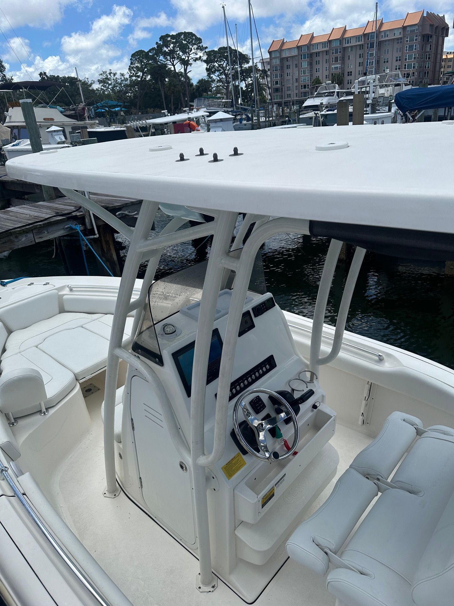 A modern boat with a helm console and seating area in a marina.