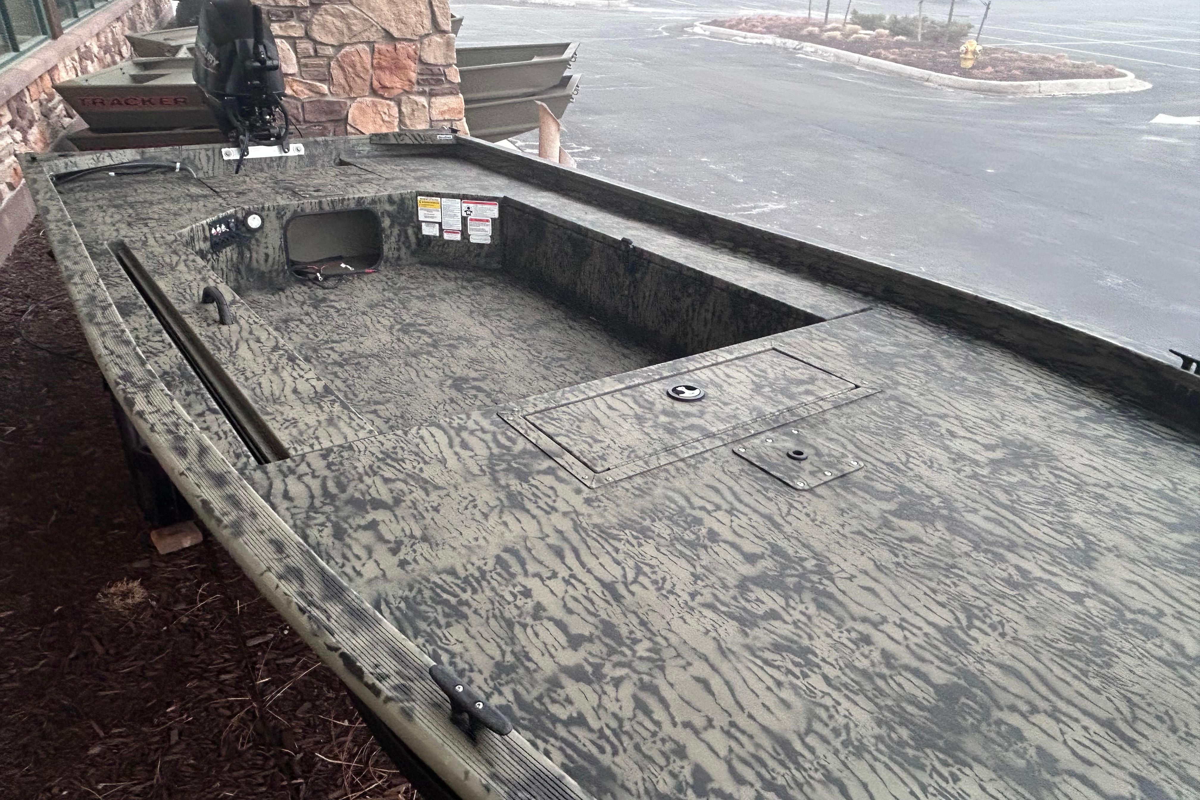 2026 Tracker Grizzly 1654 T Sportsman boat with camouflage design, parked outdoors.