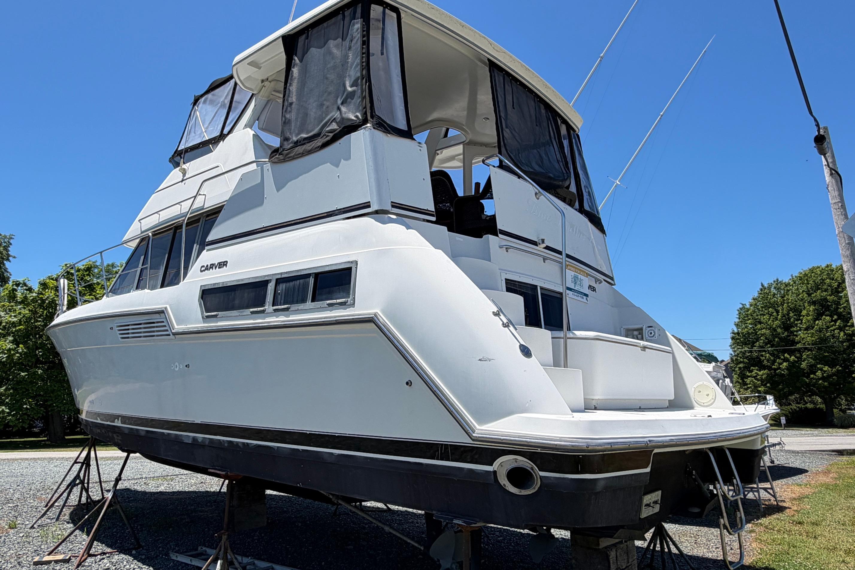 1995 Carver 356 Aft Cabin Motor Yacht on stands, exterior view under clear blue sky.