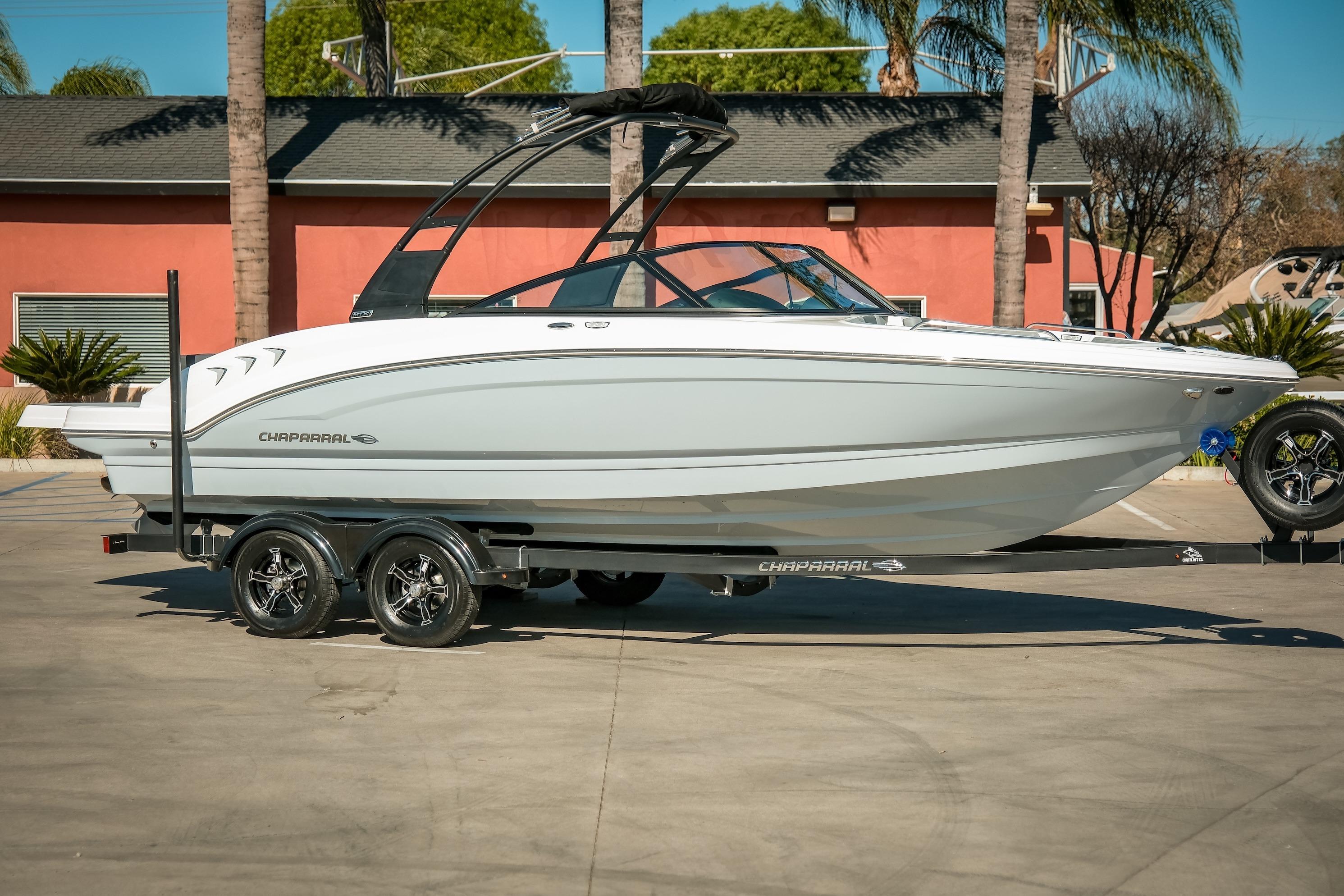 2026 Chaparral 23 SSi boat on trailer, parked outdoors with palm trees in background.