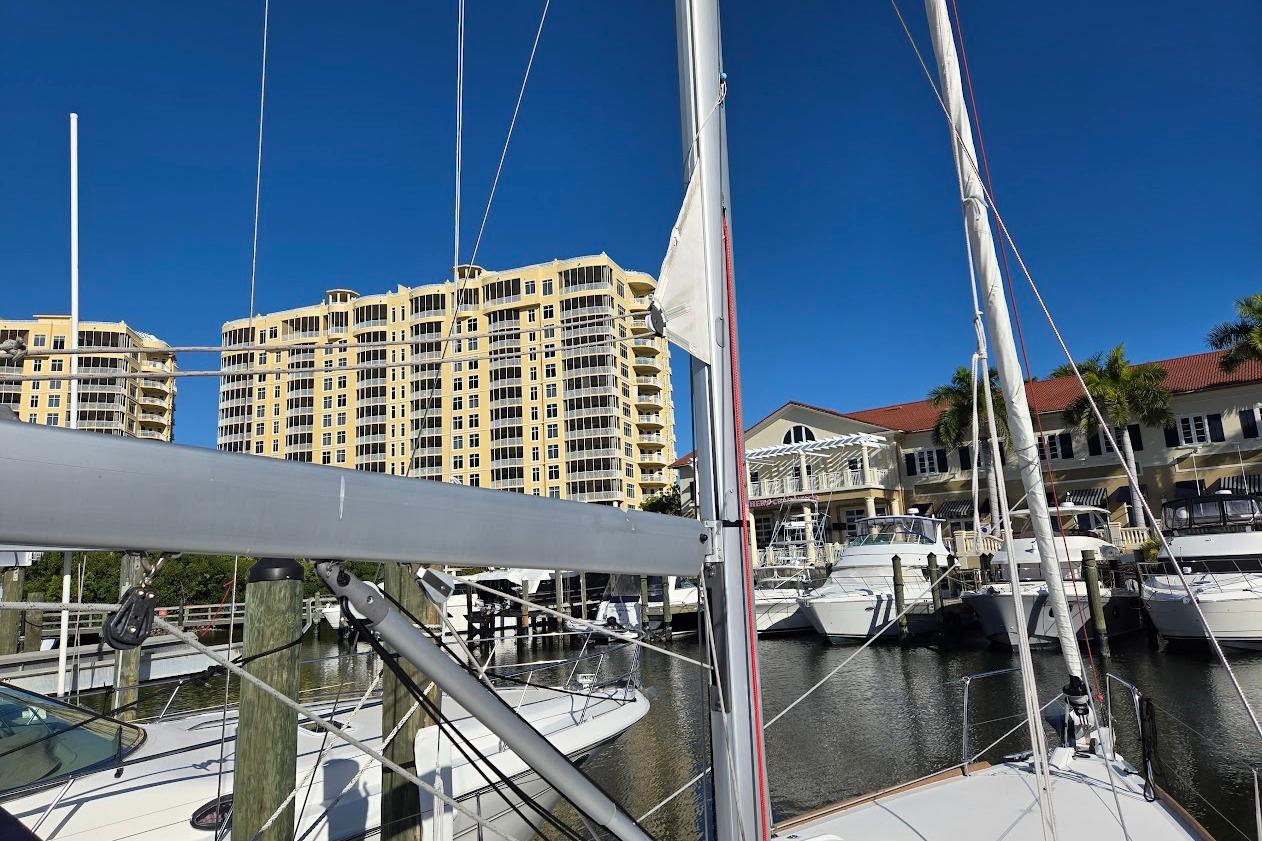 2023 Beneteau Oceanis 38.1 sailboat docked at marina with waterfront buildings.